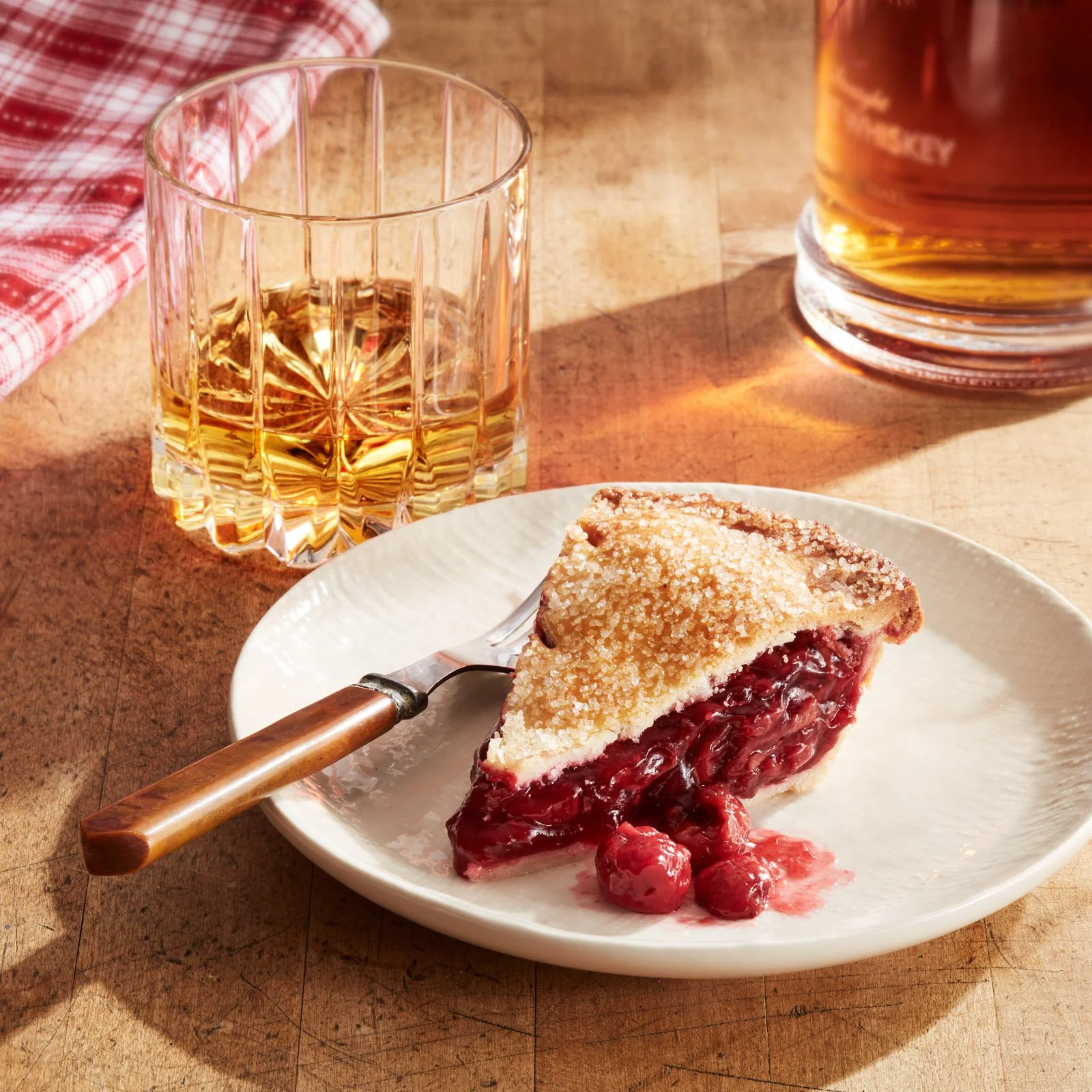 A beautiful slice of cherry pie with a glass of neat whiskey - shot for whisky advocate magazine, photographed by Jeff Harris - food styling, commercial food stylist NYC