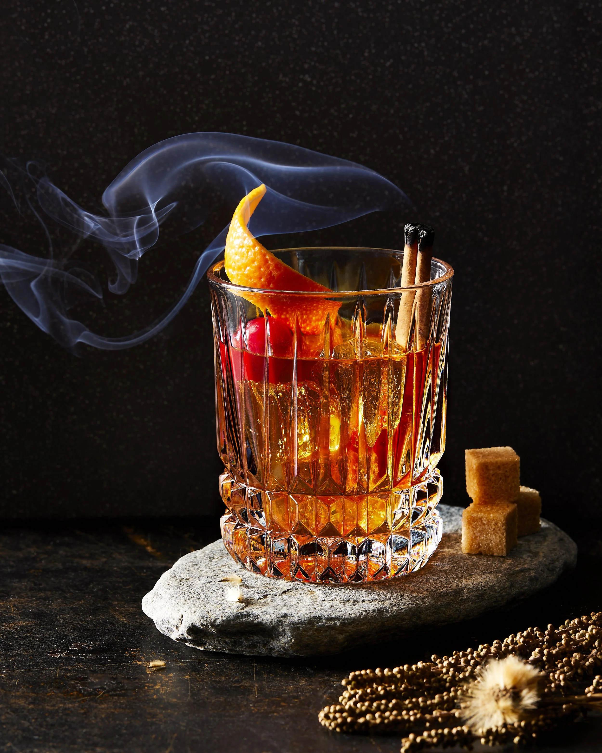 Cocktail concept shoot showing tand old fashioned cocktail with a smoking cinnamon stick - food styling, commercial food stylist NYC photographed by Rachel Vanni