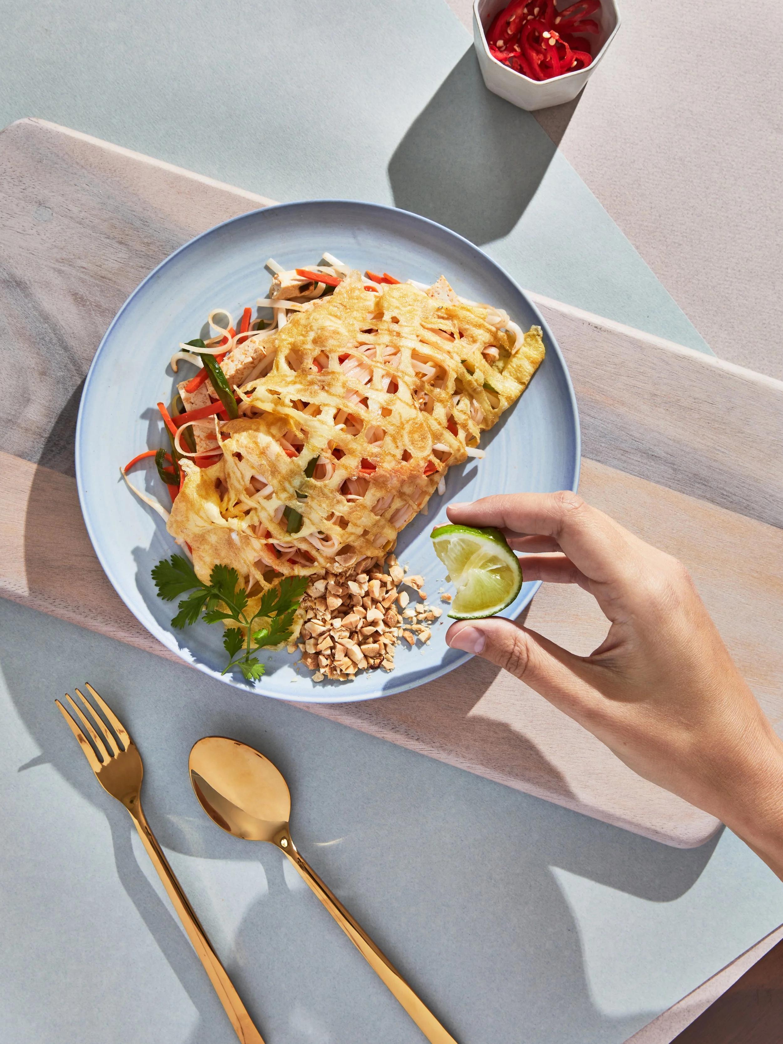 A plate of Pad Thai noodles in a traditional egg net served with toasted peanuts and lime - for a test concept shoot - food styling, commercial food stylist NYC