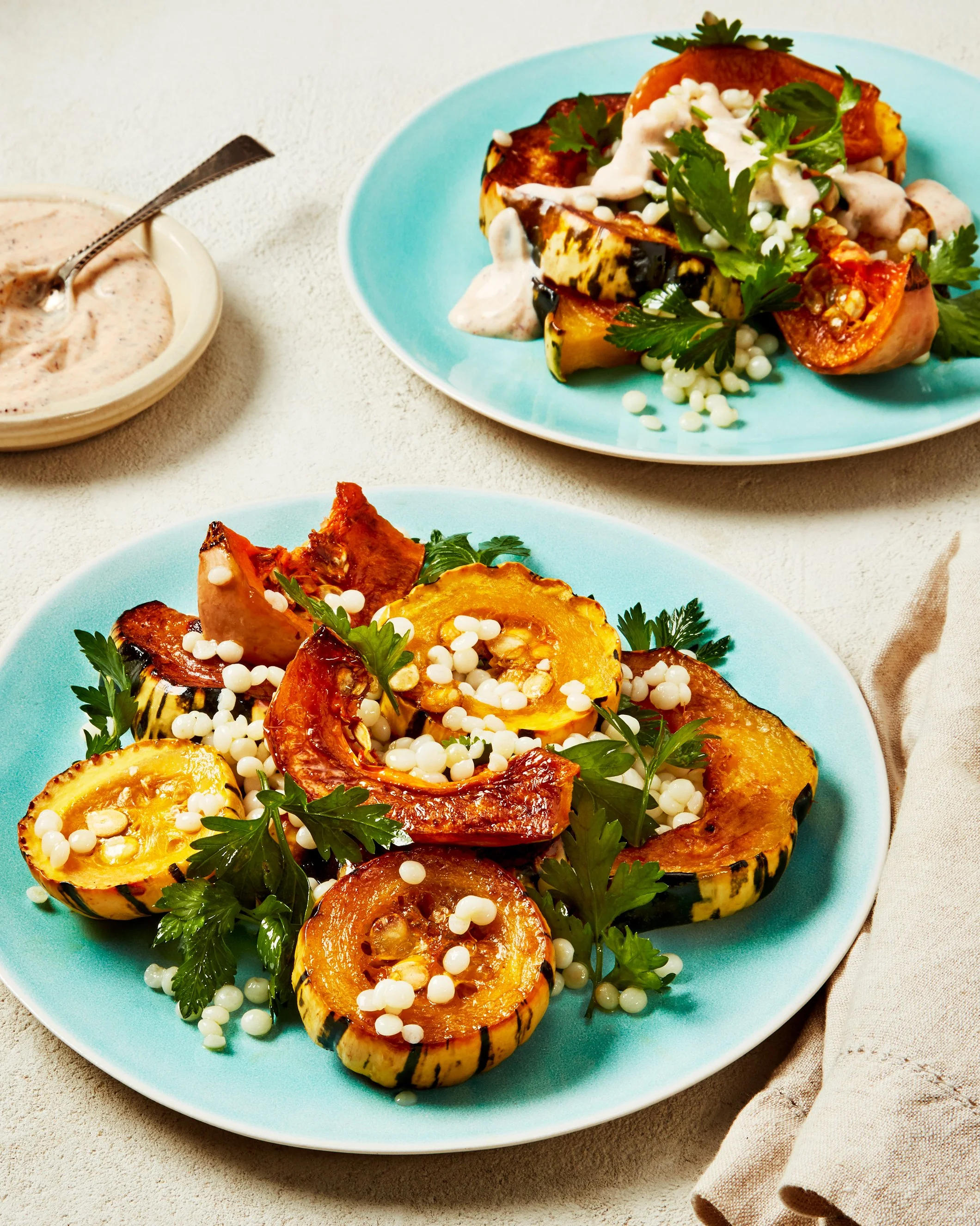 Two plates of roasted acorn squash salad with pearl couscous and herbs with a creme dressing, photographed by Emily Dryden - food styling, commercial food stylist NYC