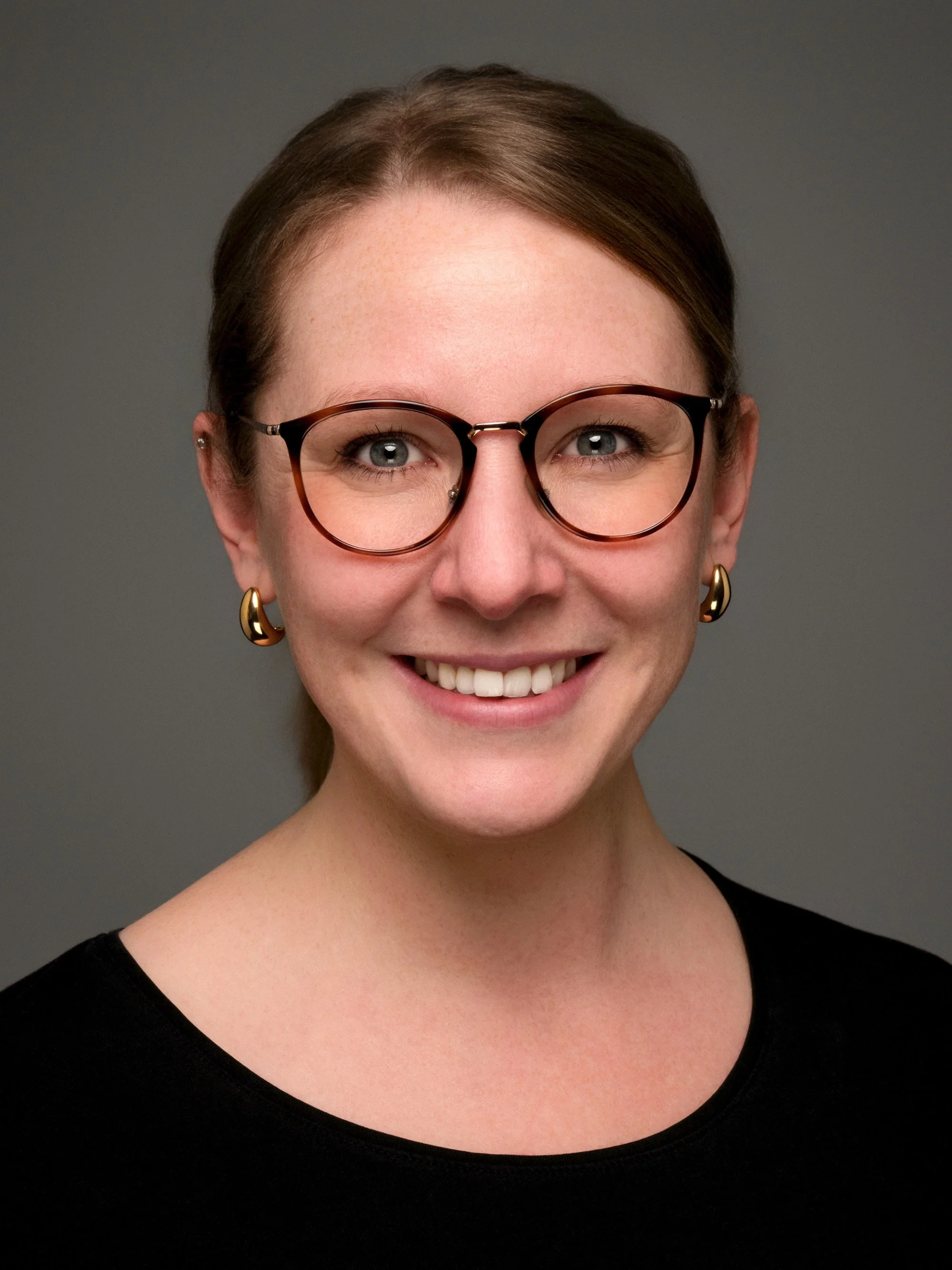Business Portrait Berlin – Frau mit Brille im schwarzen Oberteil, lächelndes Studioportrait