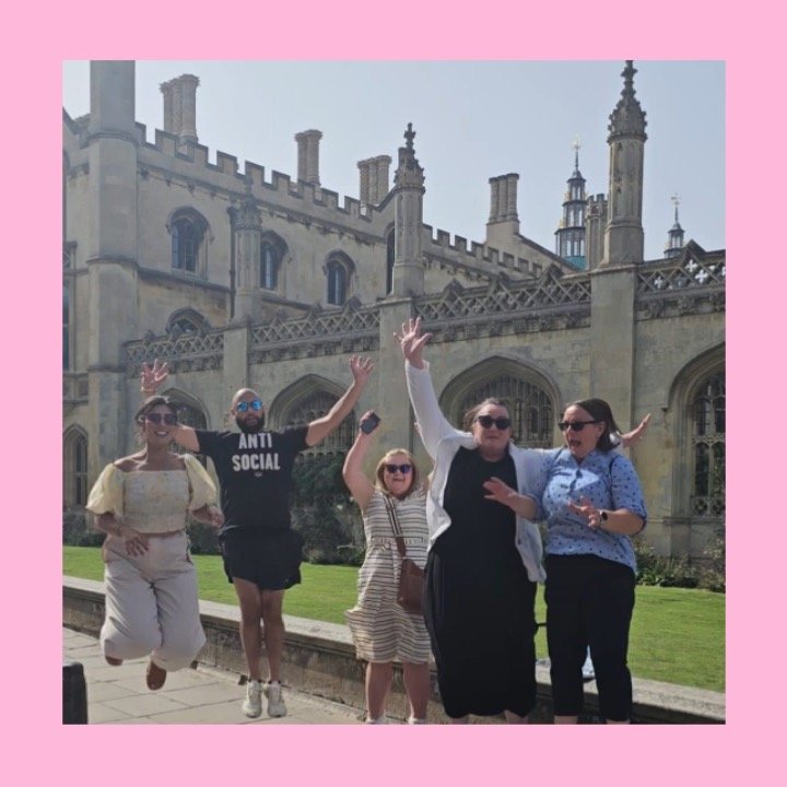 A team of 5 people jumping off the ground in front of Cambridge University Campus