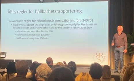 Person speaking in front of a presentation slide about sustainability reporting rules in Swedish.