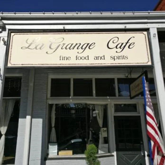 Exterior view of Lu Grange Cafe with a sign that says 'fine food and spirits' and an American flag outside
