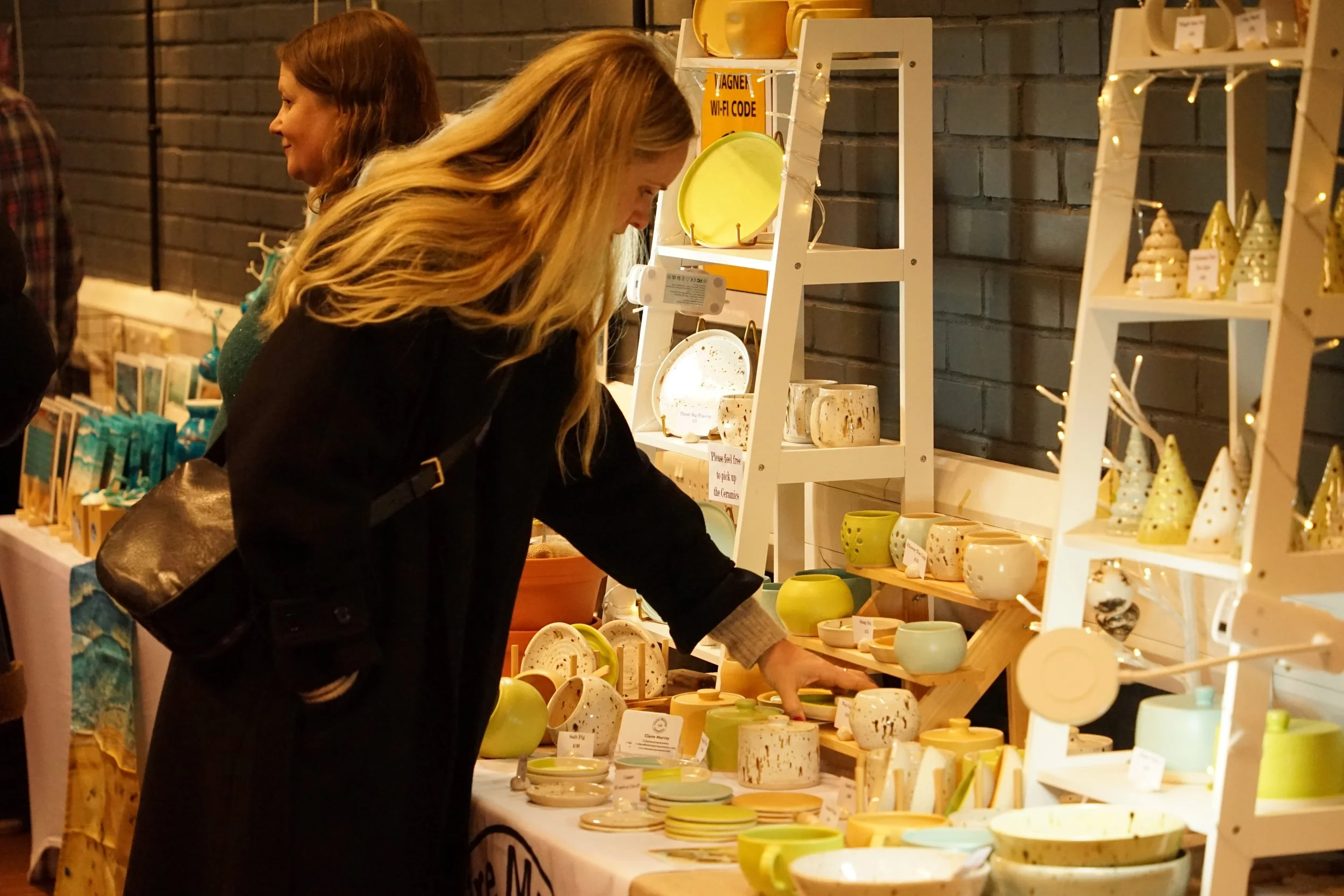 a visitor picking up a homemade cup on a ceramics stall at Wagner Hall