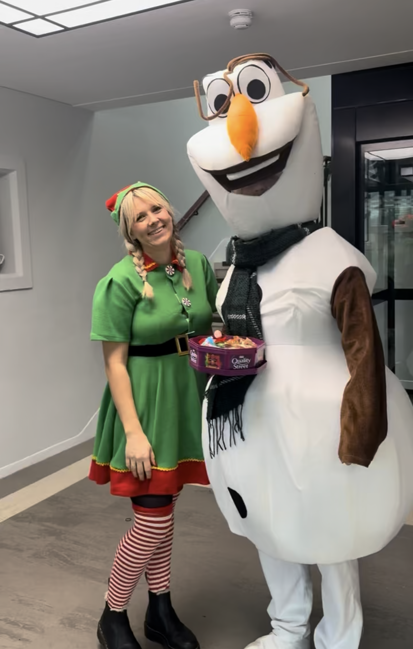 an Elf smiling next to Olaf, holding a box of chocolates