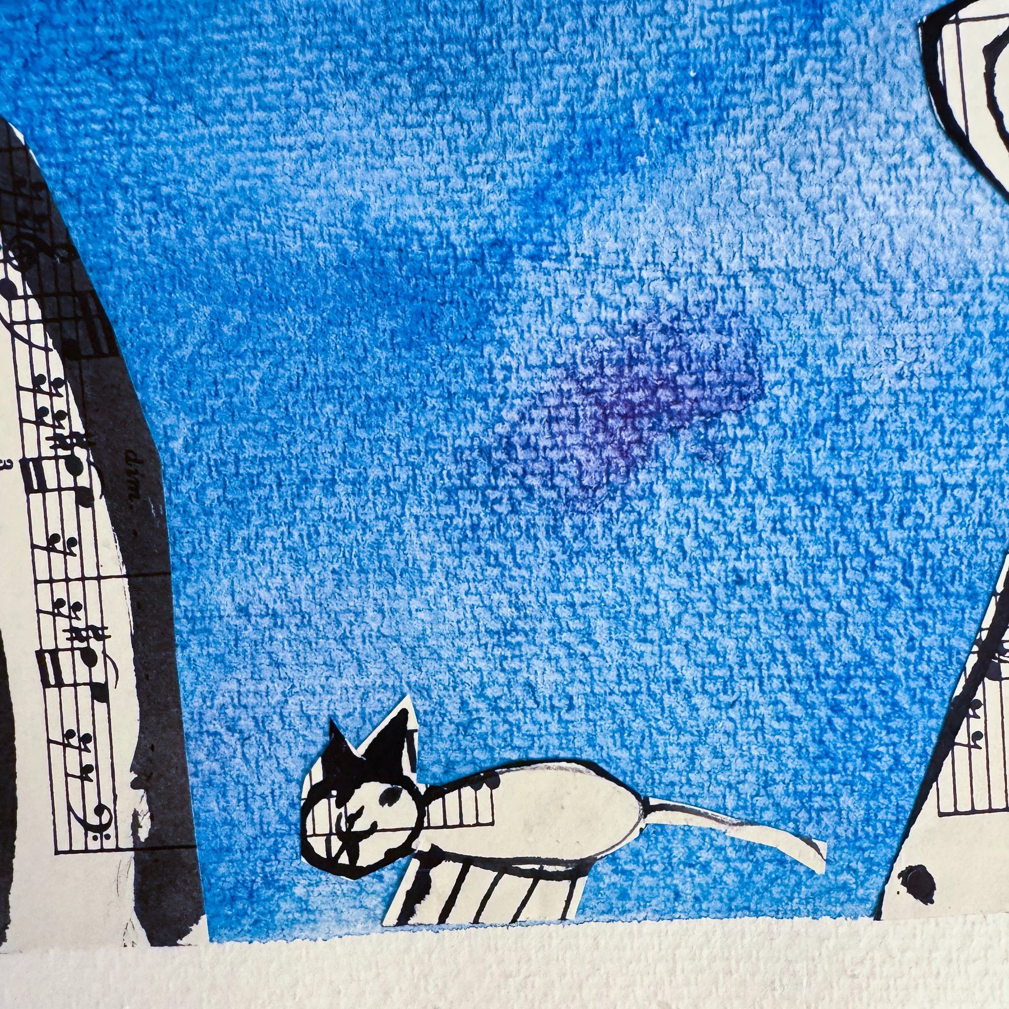 A blue piece of paper with a black and white cat illustration and partial sheet music on the edges.