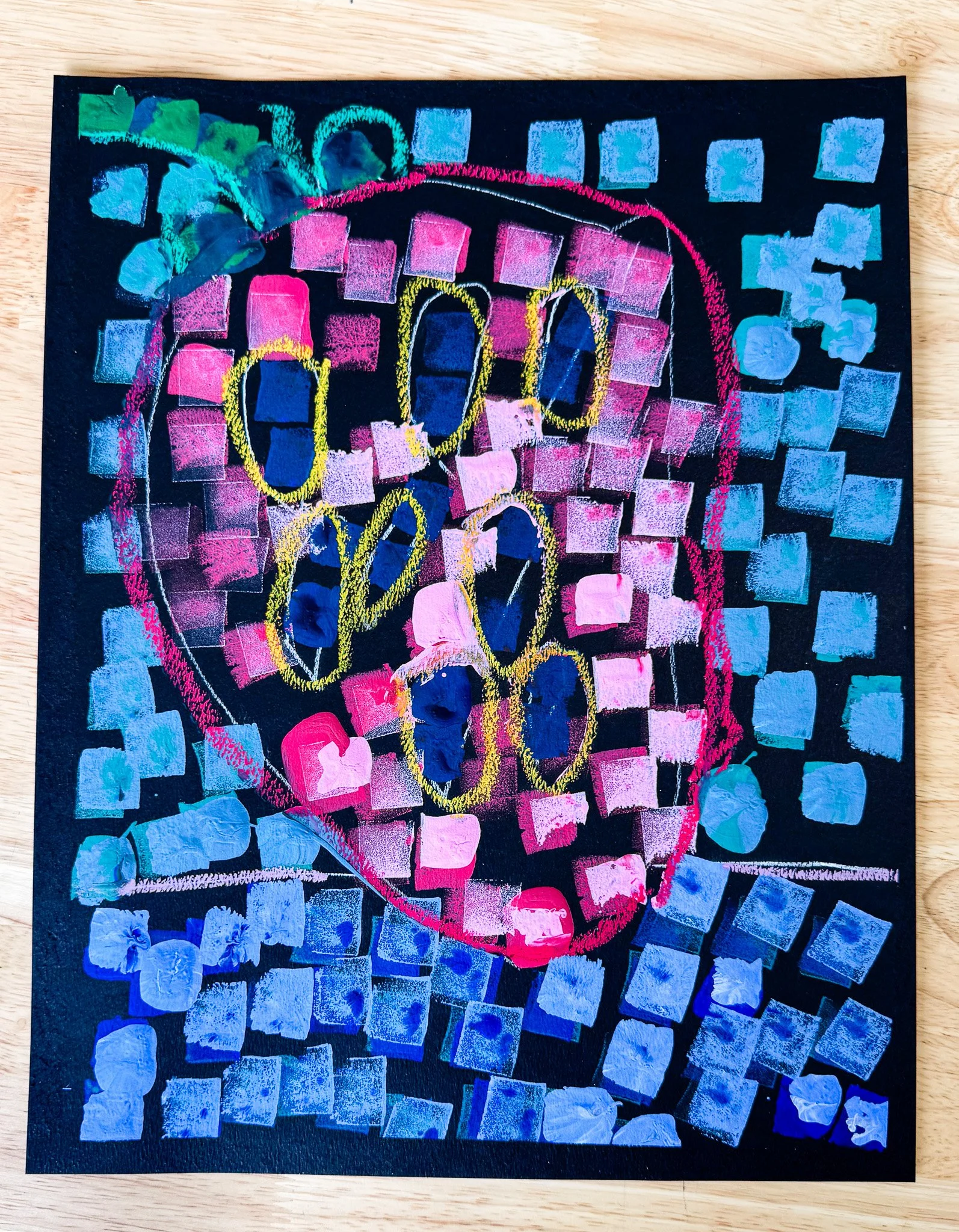 Colorful abstract art of a skull created with pink, blue, yellow, and teal paint, featuring a geometric background of small squares and circles.