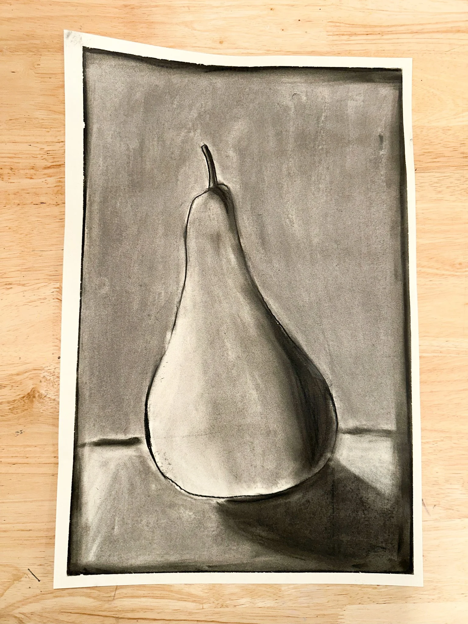 Black and white drawing of a pear on a table, with a shadow cast to the right.