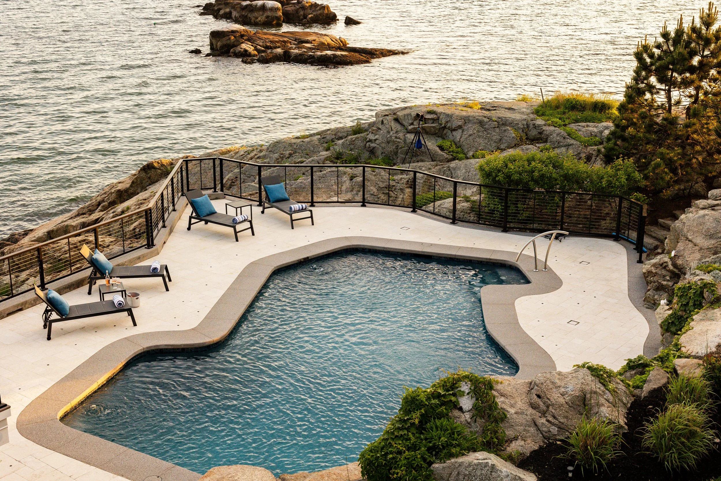 Coastal swimming pool with loungers, towels, and ocean view.