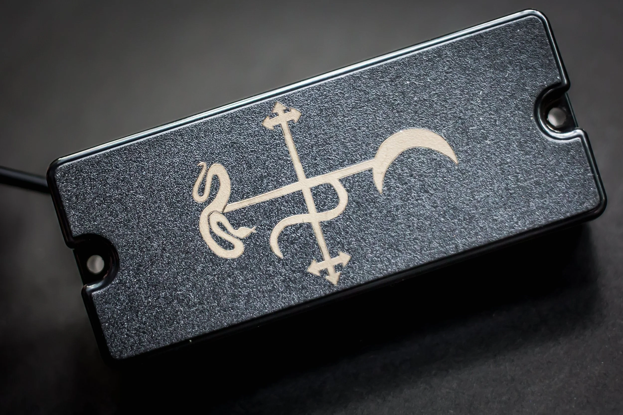 Artistic shot of a high output Arcana humbucker with custom sigil including a crescent moon and snake
