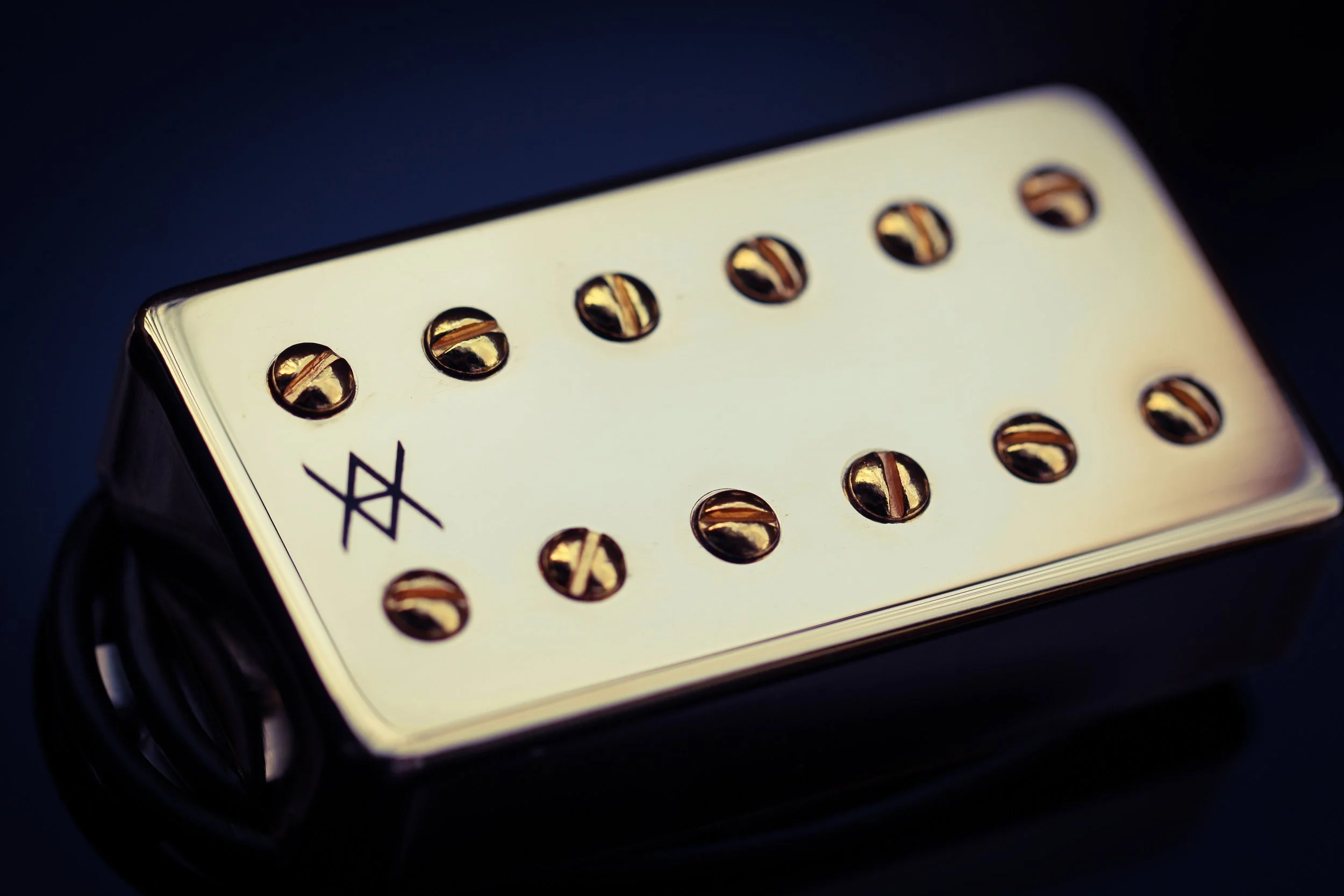 Guitar pickup with screws and a humbucker bridge, viewed from an angle.