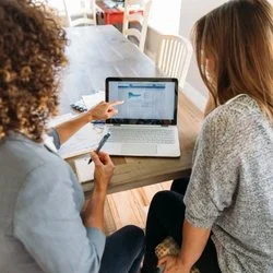 Two people looking at a laptop screen trying to understand if ai for personal finance is right for them.