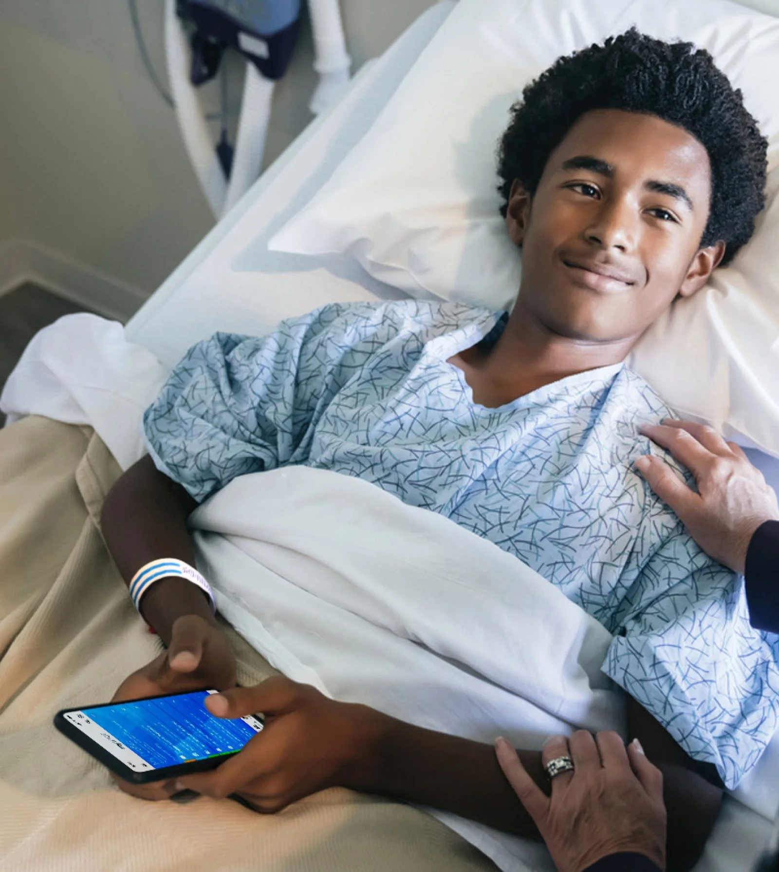 a young man in a hospital bed while using the mySPOT app