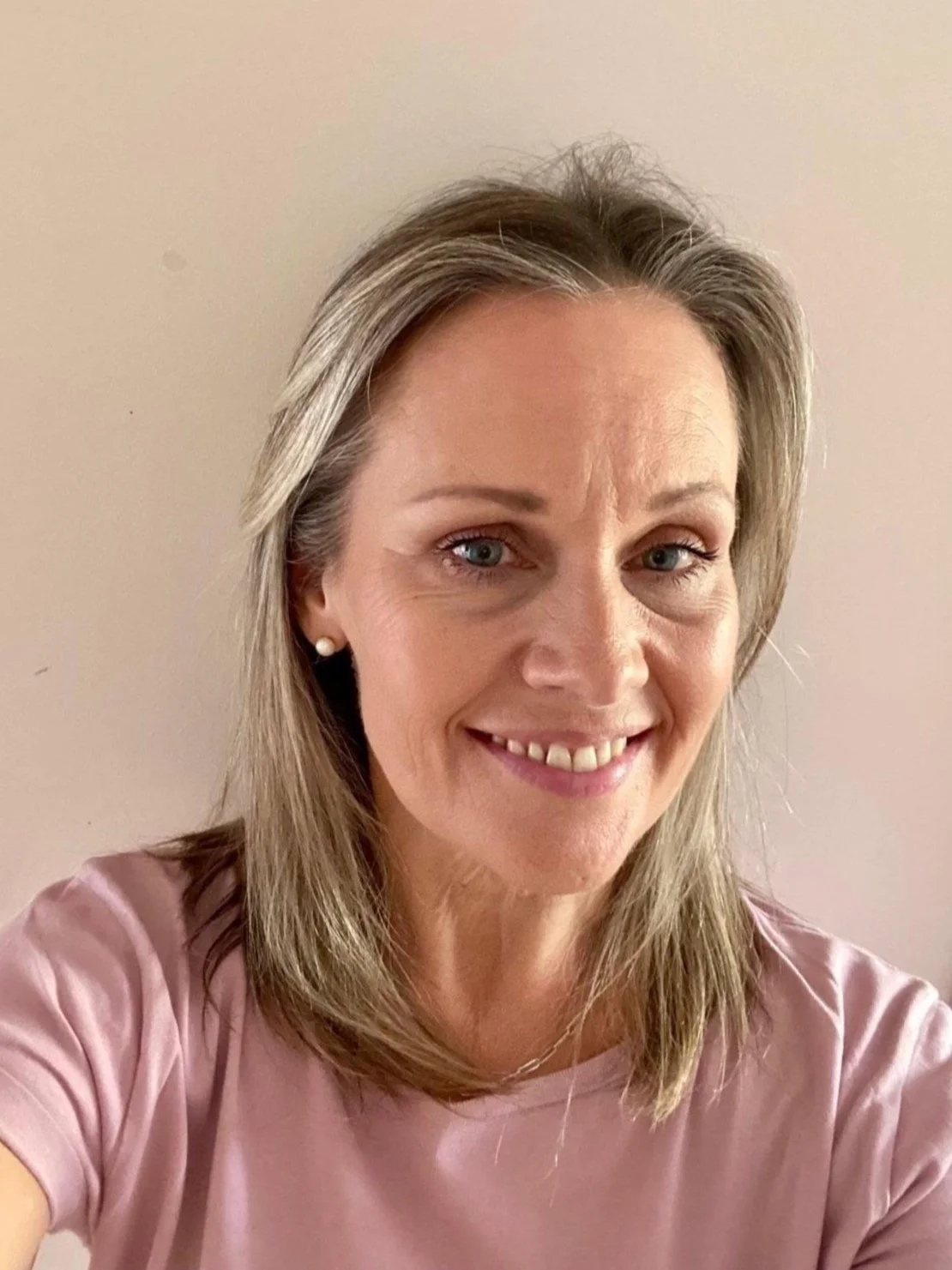 Studio Teacher Nadine smiling at the camera, wearing a light pink top, against a plain background.