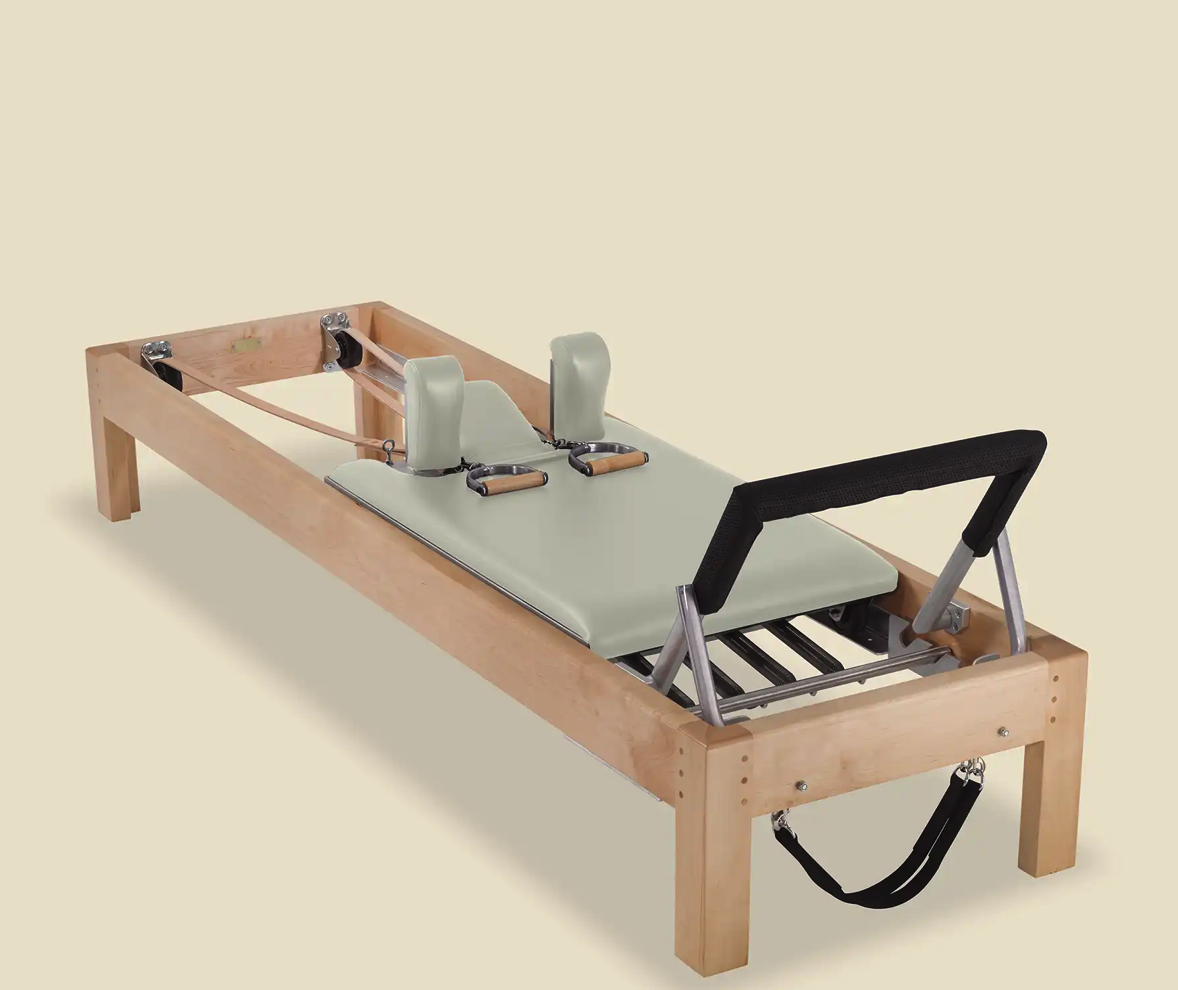 Image of a Classical Pilates Reformer with a wood frame and sage green upholstery