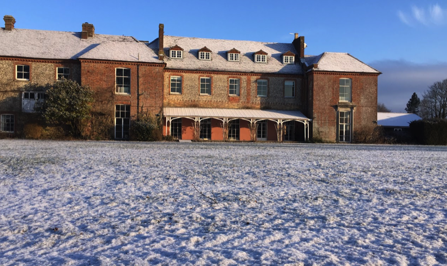 The historic brick Lavant House building with snow-covered roof and lawn