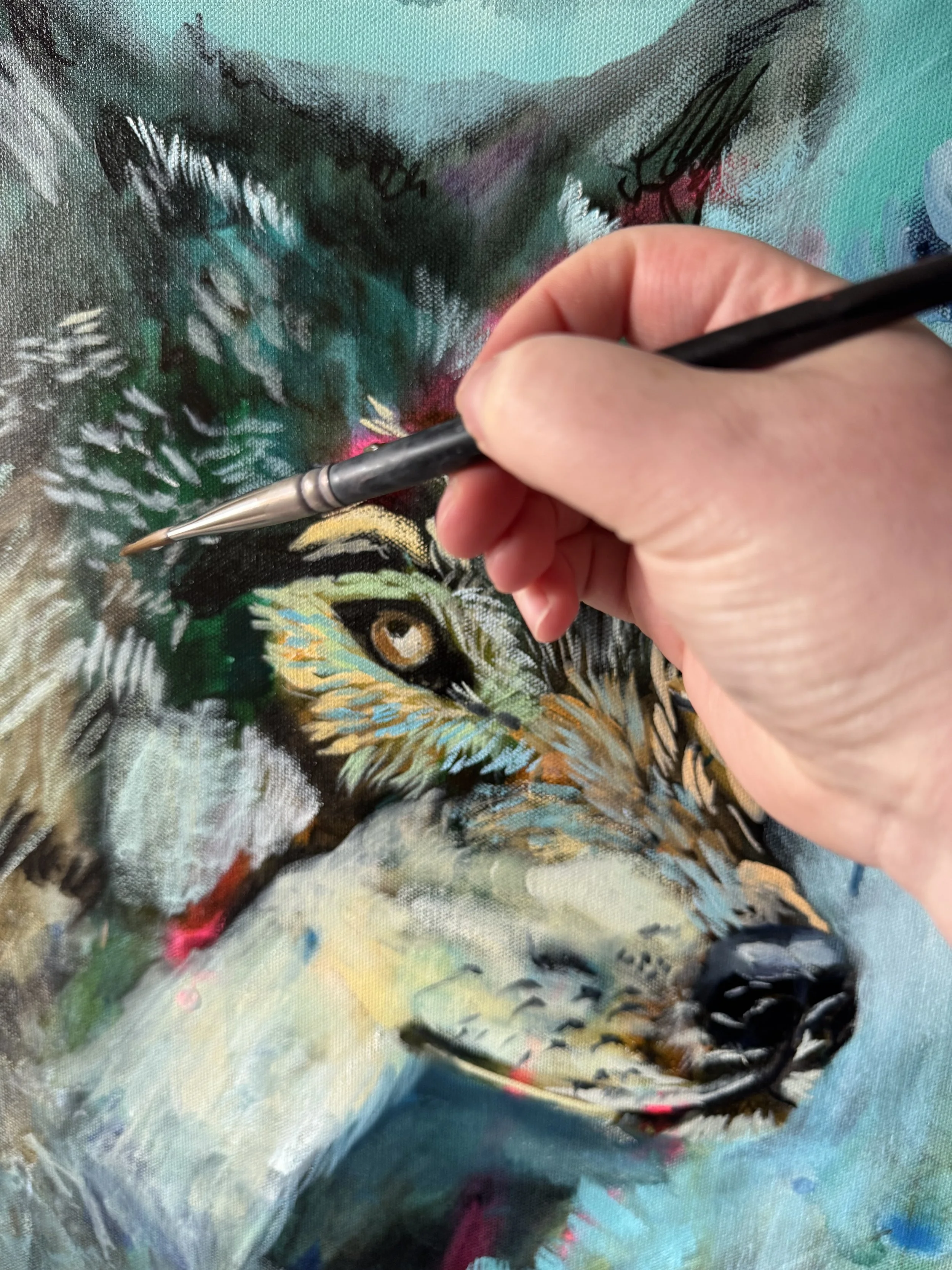 Close-up of a canvas being painted with a colorful, abstract design, showing a person's hand holding a paintbrush.