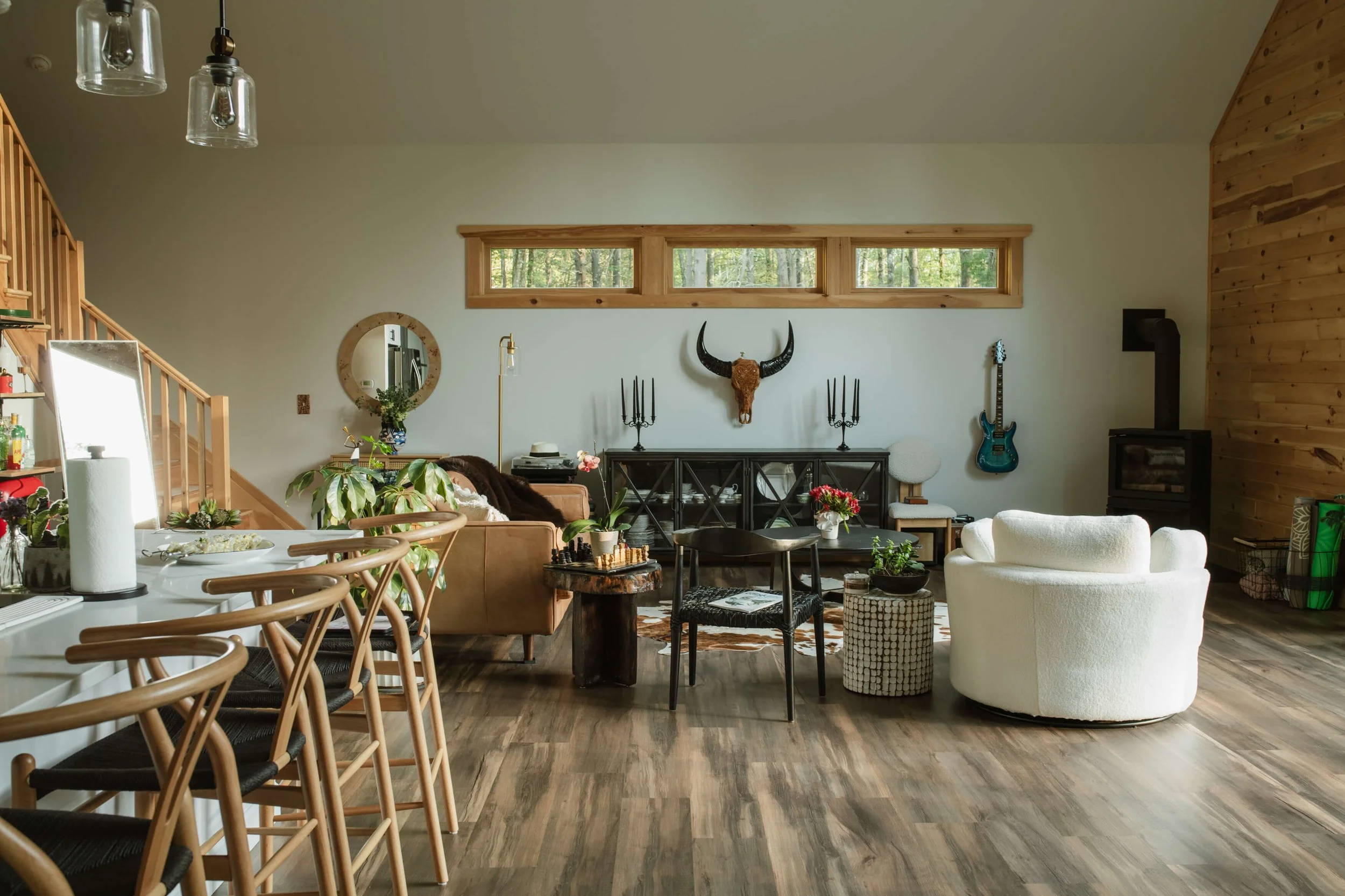 Living Room- Interior Sunlit open-concept living room with hardwood floors, cozy sofa, and Catskills forest views.