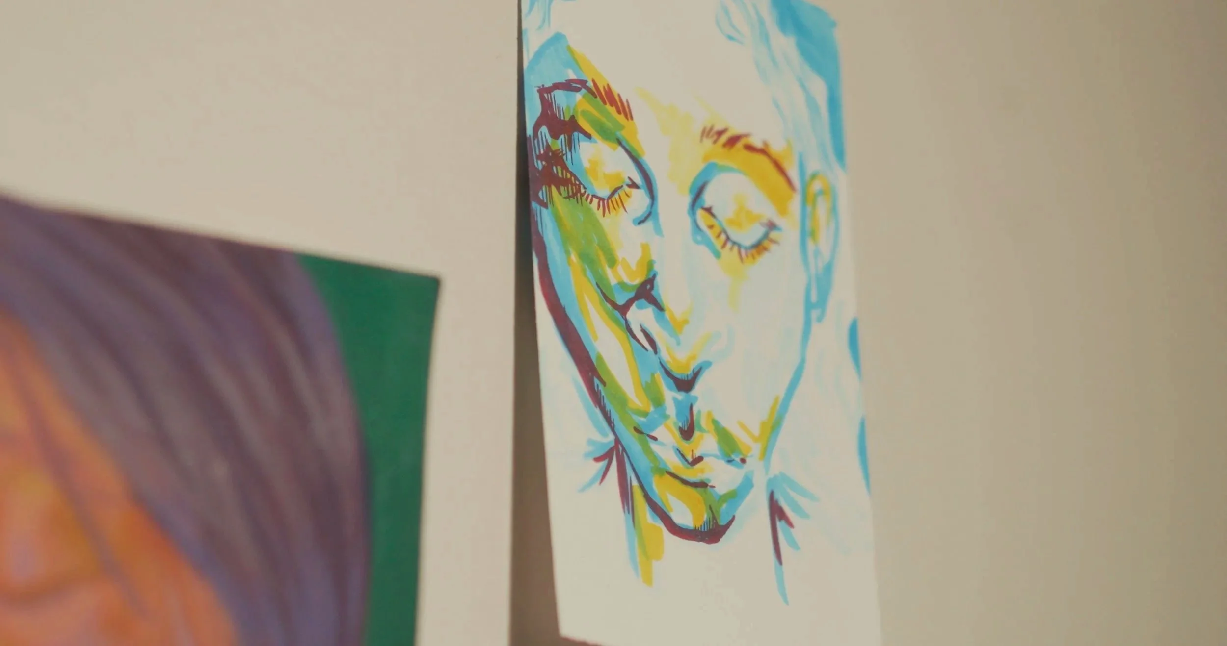 A colorful line drawing of a person's face with closed eyes, using shades of yellow, blue, red, and green.
