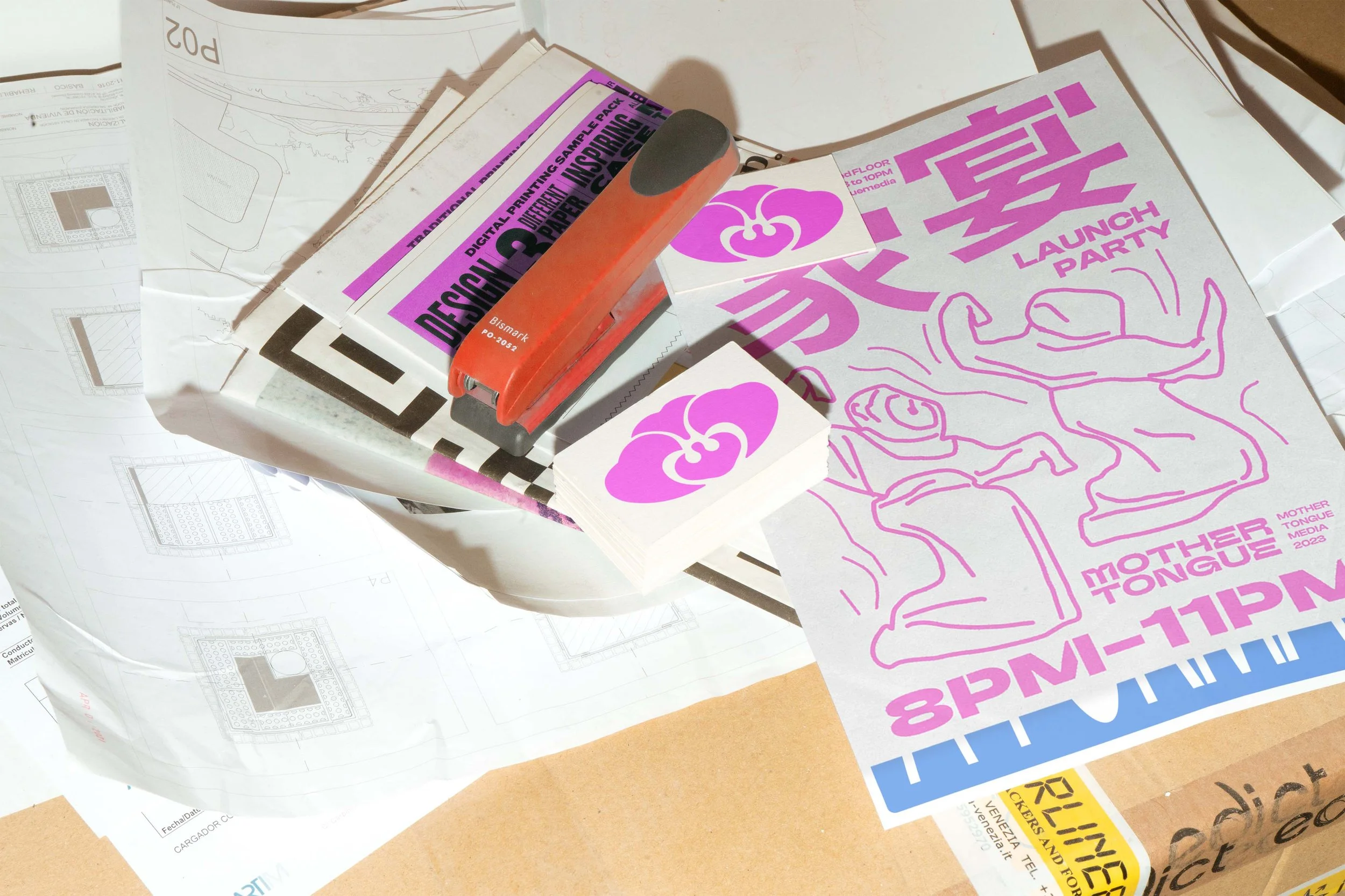 Stacked flyers with pink and purple graphics and text, a rubber stamp, and scattered paper documents on a surface.