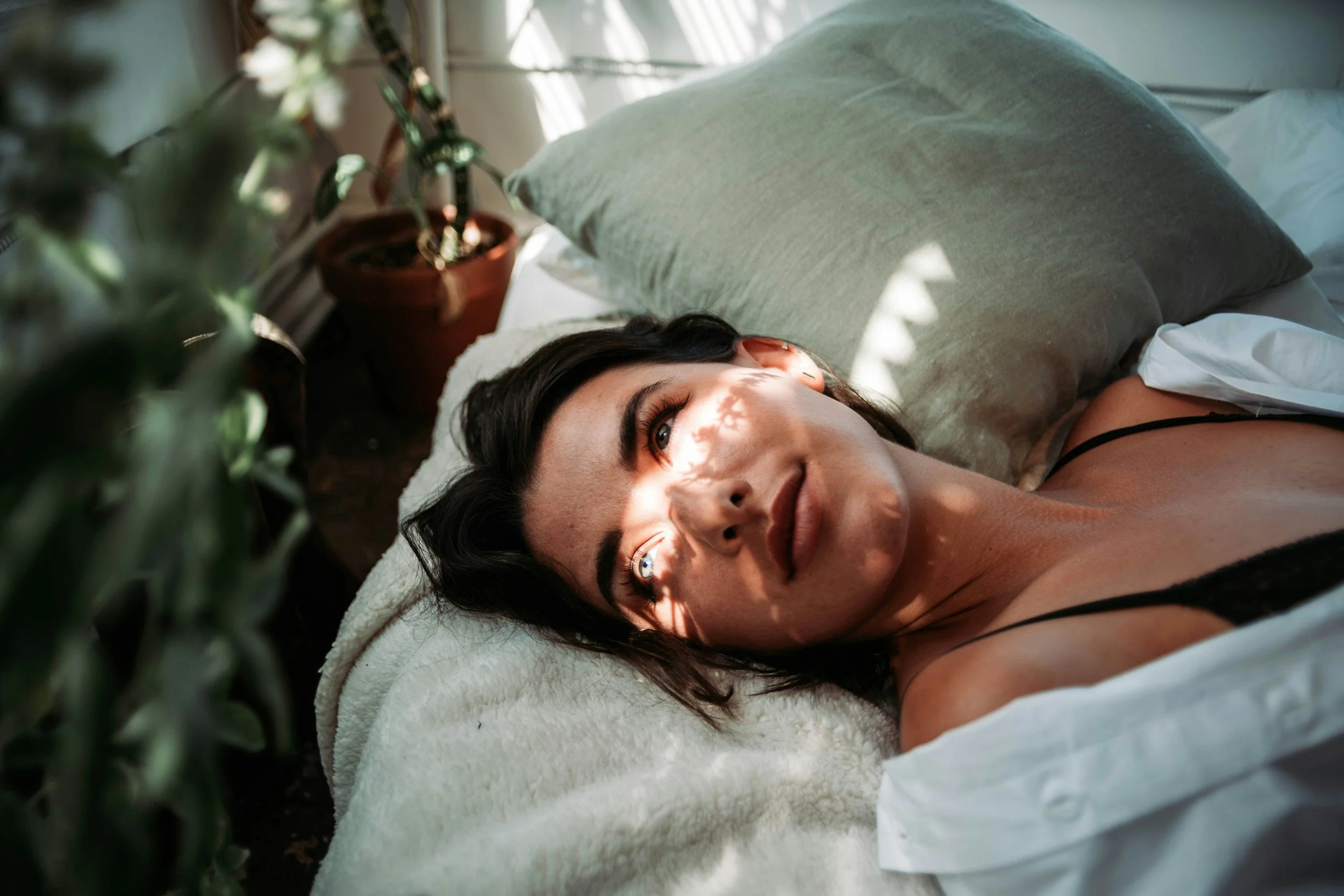 Woman sitting peacefully with sunlight on her face, practicing somatic therapy techniques for relaxation and nervous system regulation.
