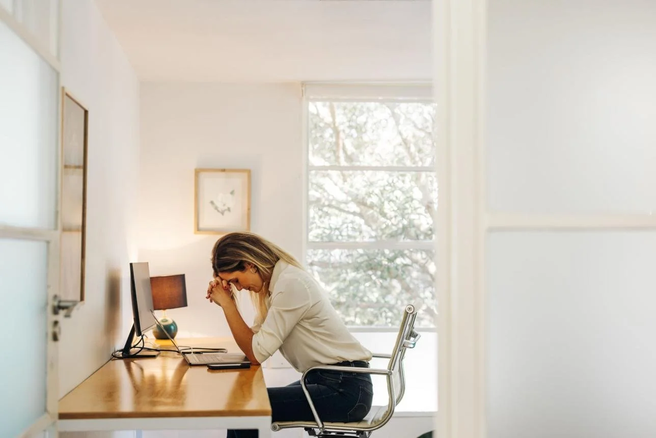 Adult experiencing burnout and emotional exhaustion while working, representing functional freeze and chronic stress recovery therapy in McKinney Texas