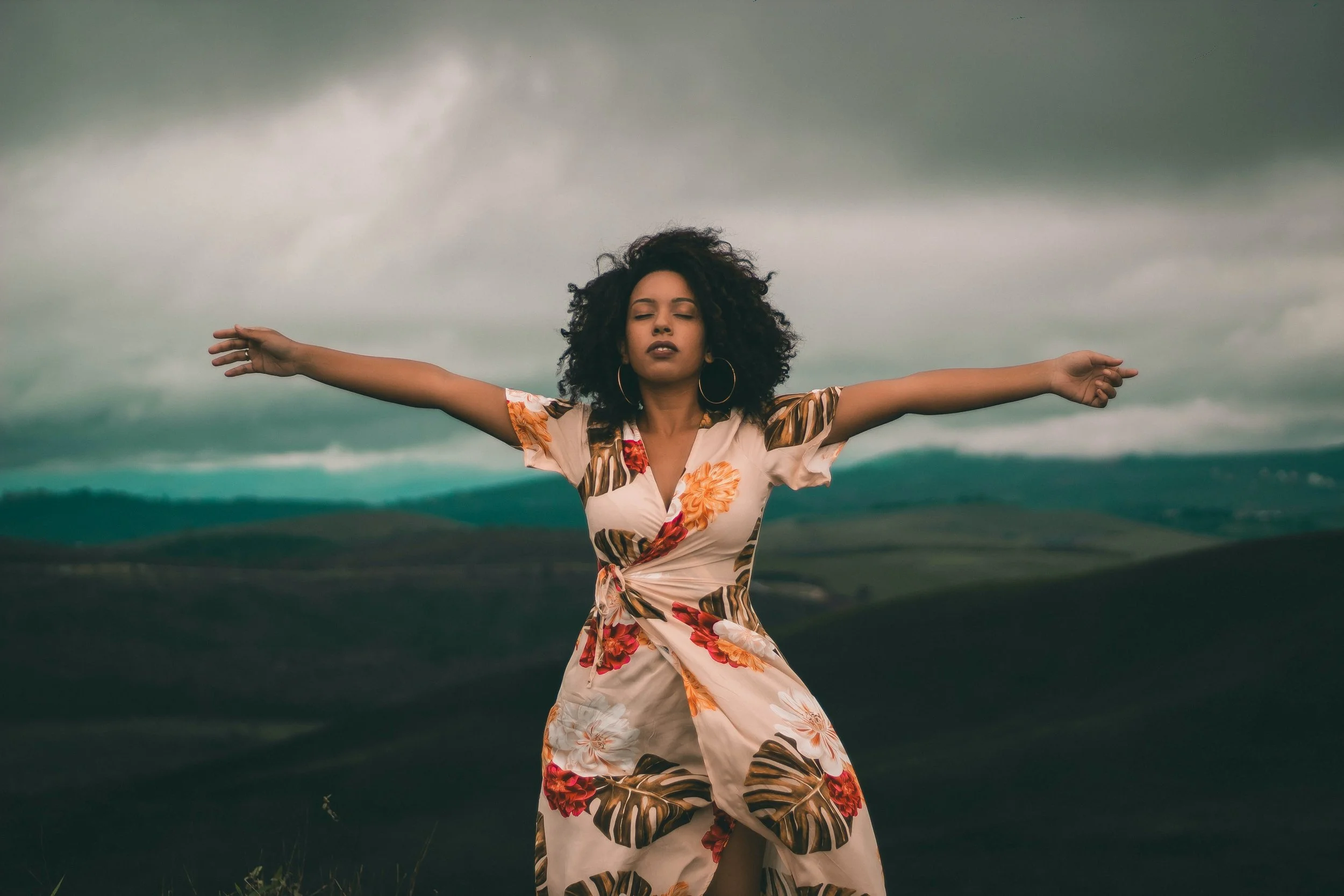 A woman with eyes closed and arms outstretched.
