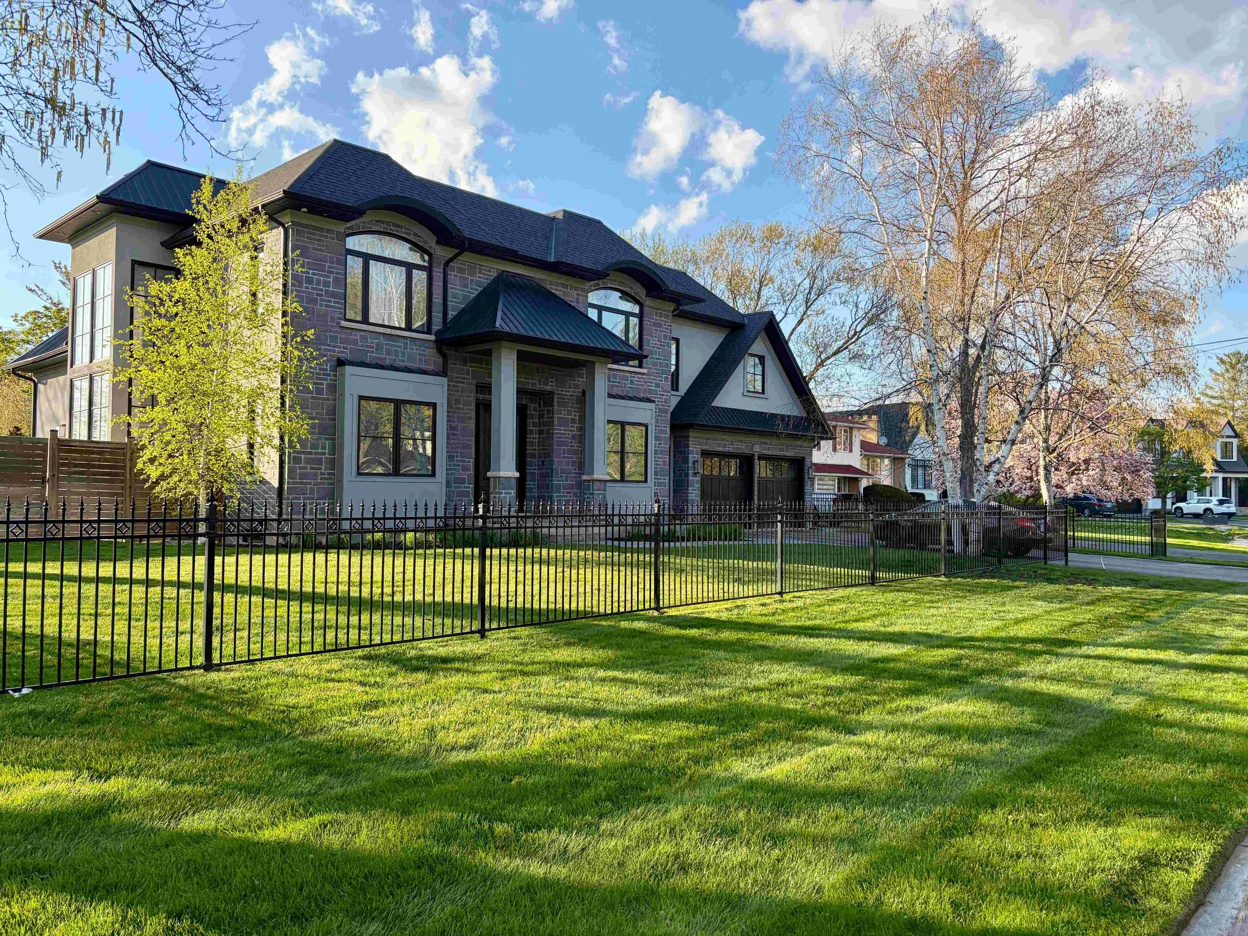 Immaculate front lawn featuring premium curved grass stripes and perfectly manicured garden beds at a luxury residential property in the Bronte Village neighborhood of Oakville, maintained by JC Priority Landscaping.