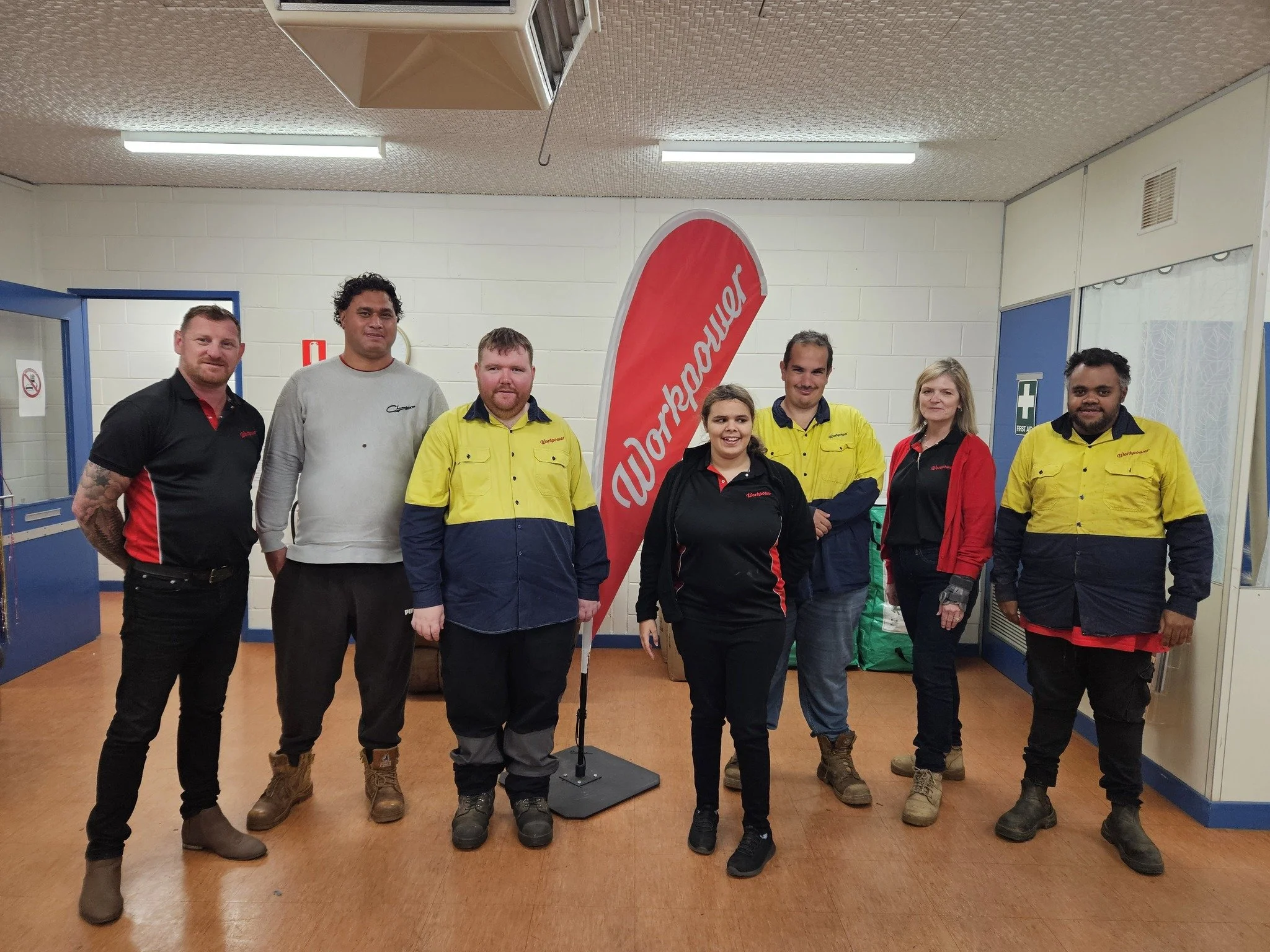the workpower kalgoorlie team standing in front of a workpower flag