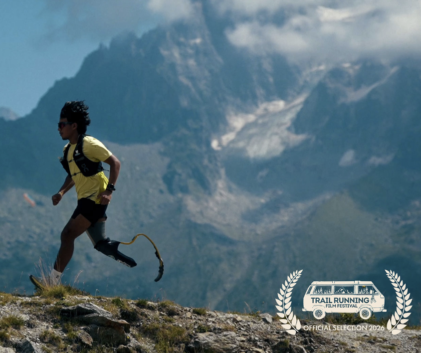 Ecuadorian adaptive athlete Yahir running with a blader on left leg in a yellow shirt on a ridge with mountains in background