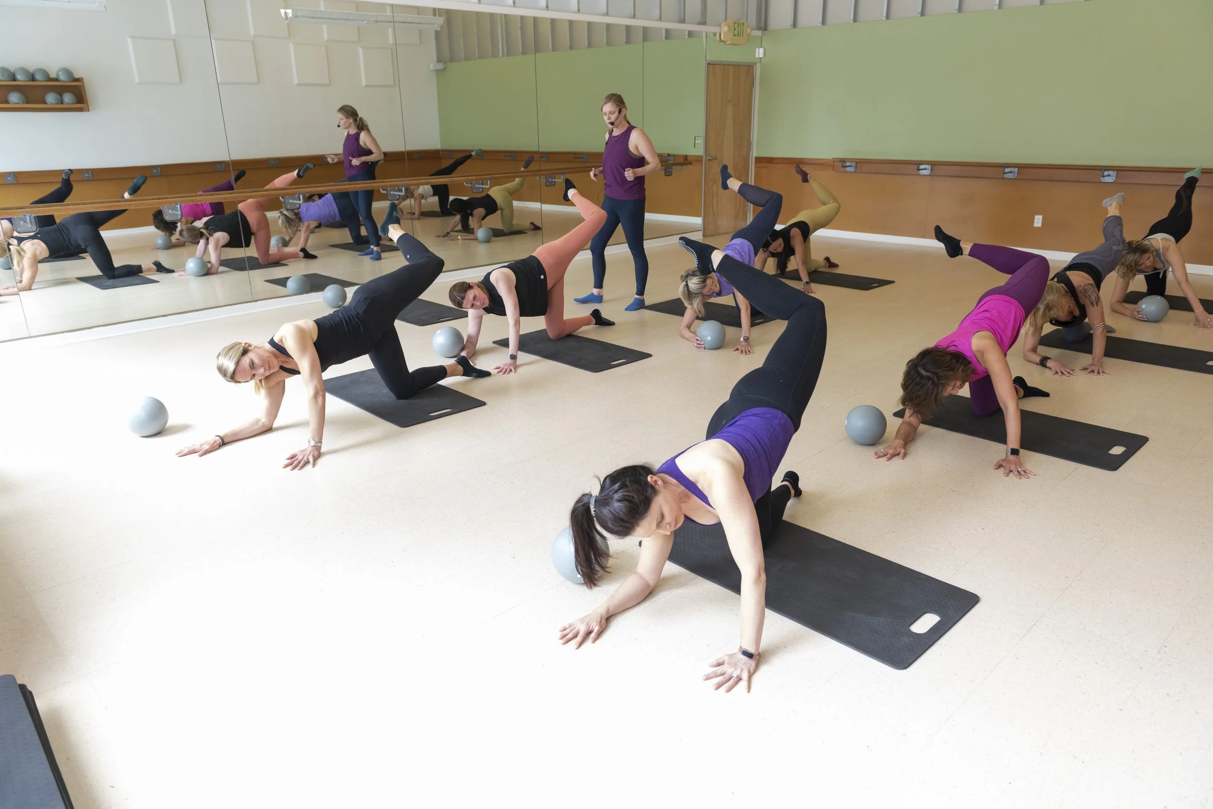 A group of clients doing a barre workout on their hands and knees at Studio 1024