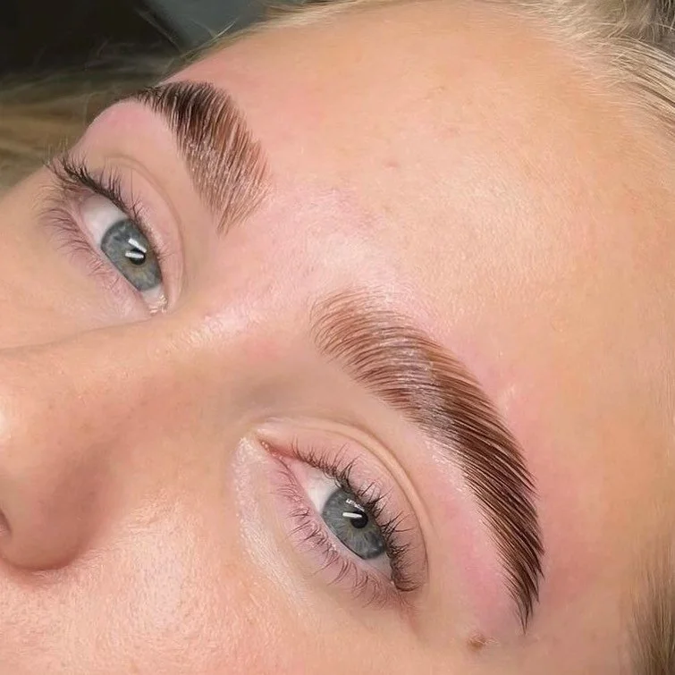 Close-up of a woman's face showing freshly groomed and shaped eyebrows and blue eyes.