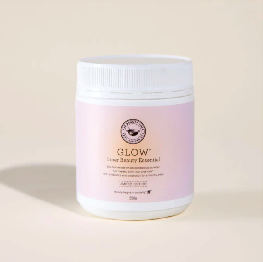 A white container of Glow Inner Beauty Essential with pink label, featuring a black logo and text, set against a plain, light-colored background.