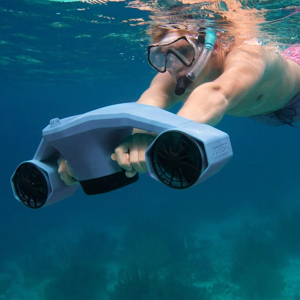 A woman snorkeling underwater wearing a mask and snorkel, holding a handheld water heater.