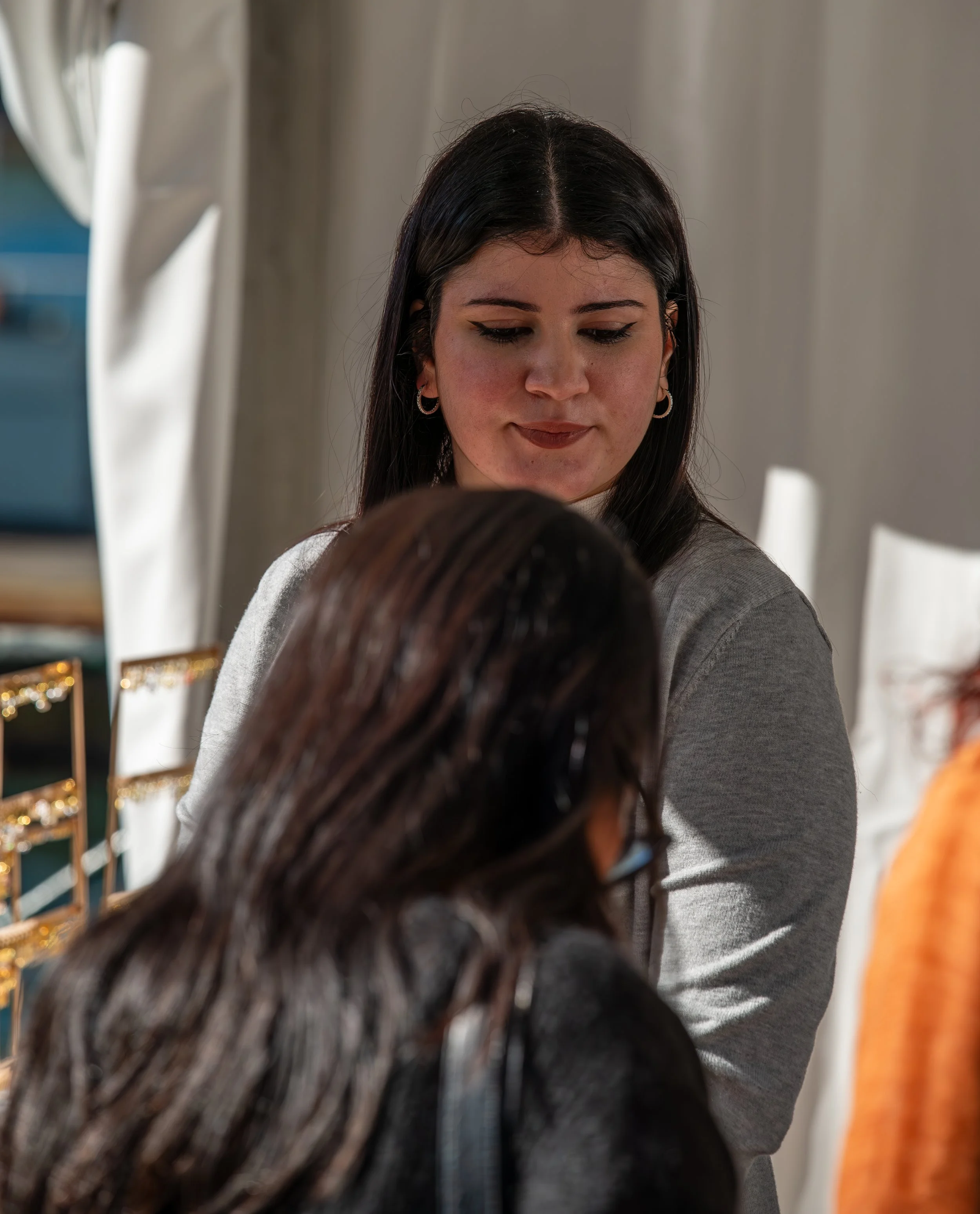 Two women engaging in a conversation indoors, with jewelry display in the background.