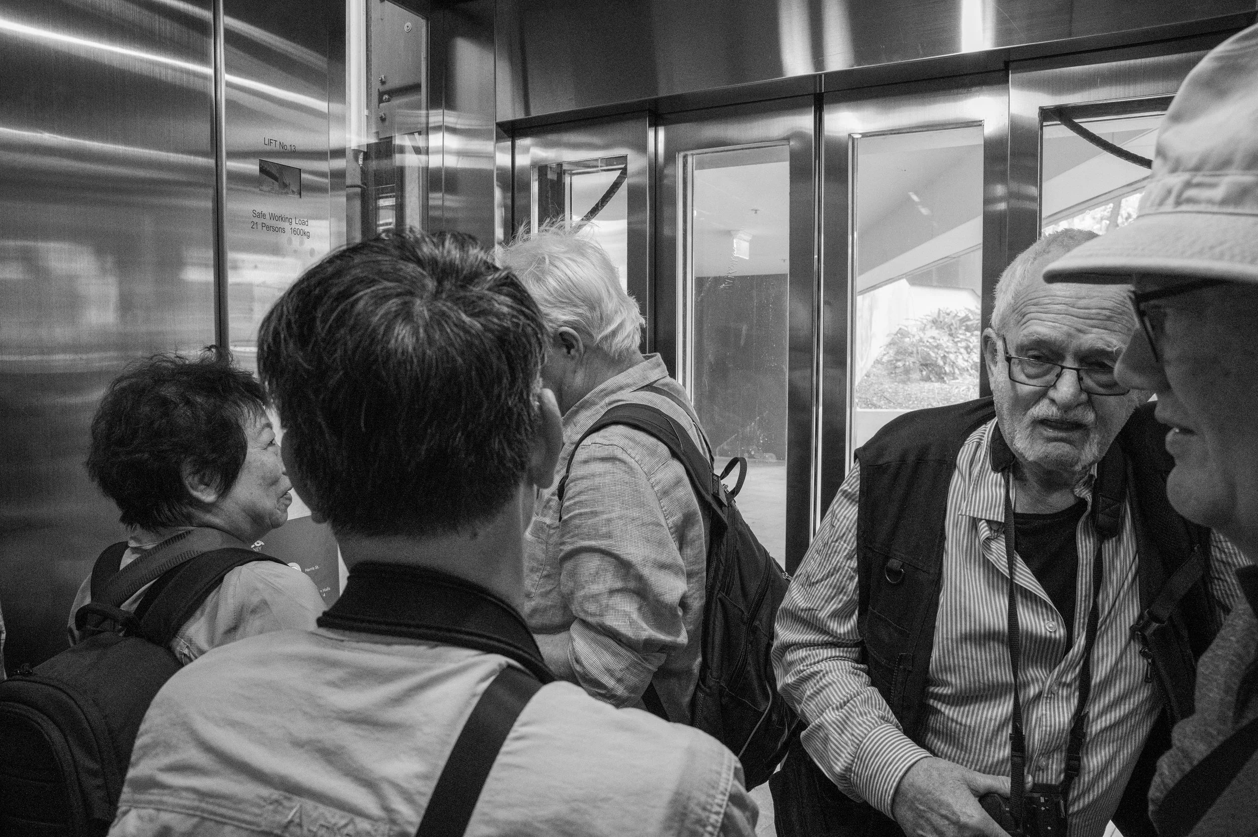 Group of diverse people waiting in an elevator, engaged in conversation.