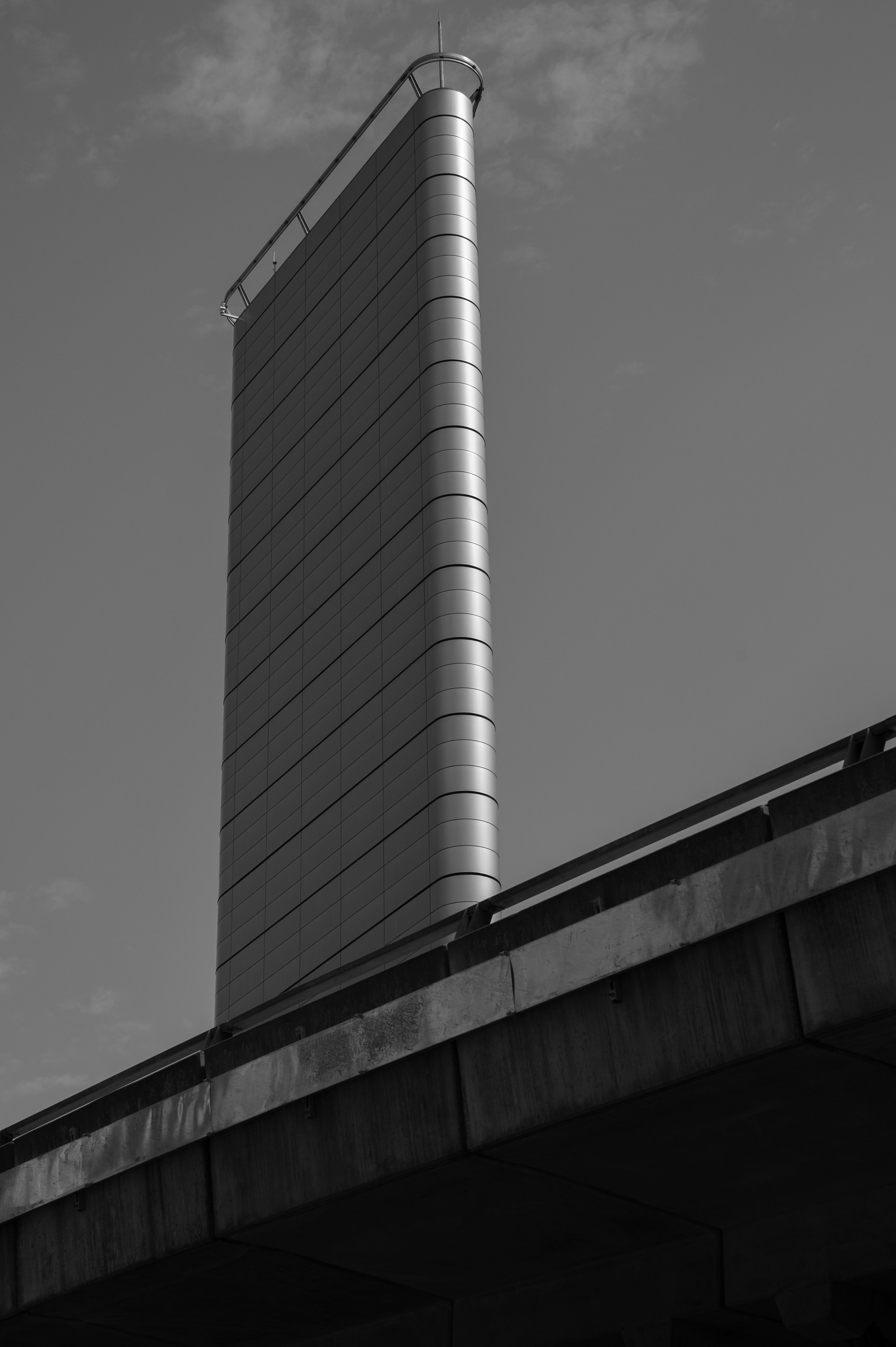 Black and white photo of a tall, modern skyscraper with curved edges, seen from below.