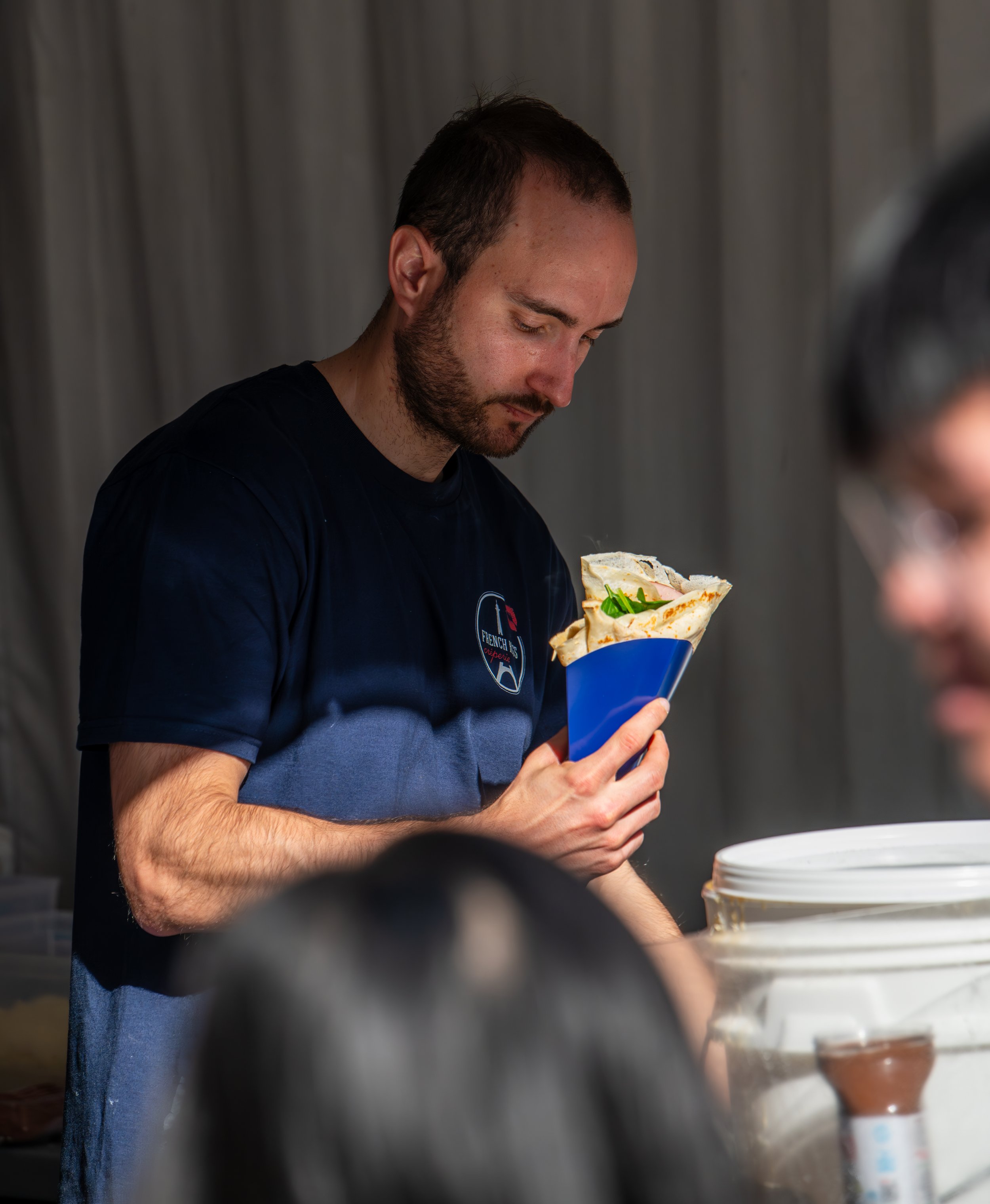 A man holding a cup with a pastry inside, looking at it with interest.