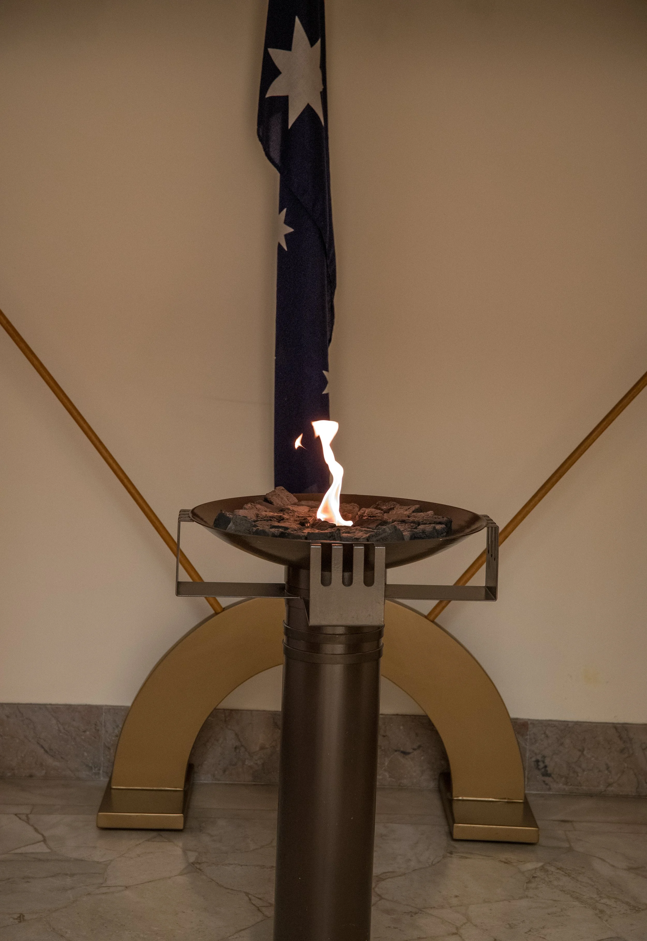 Indoor fireplace with a small flame and rocks on top, with a flag featuring a star pattern on a pole behind it.