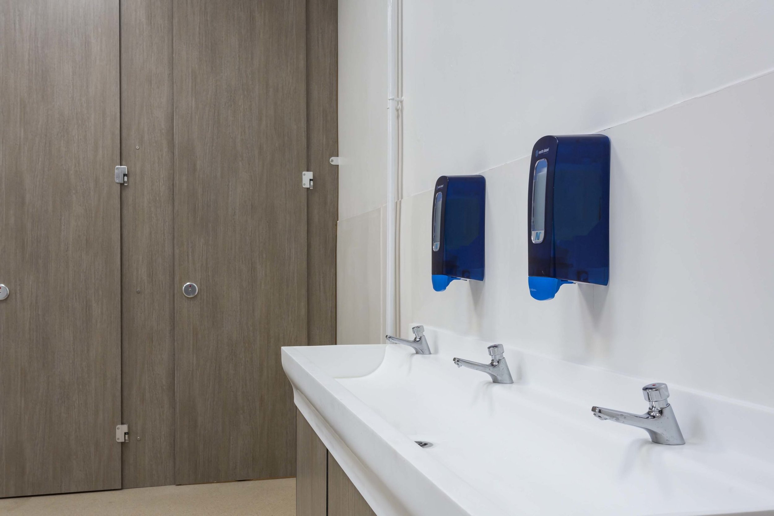 trough with soft touch taps and soap dispensers, woodgrain private cubicles at CNS.jpg