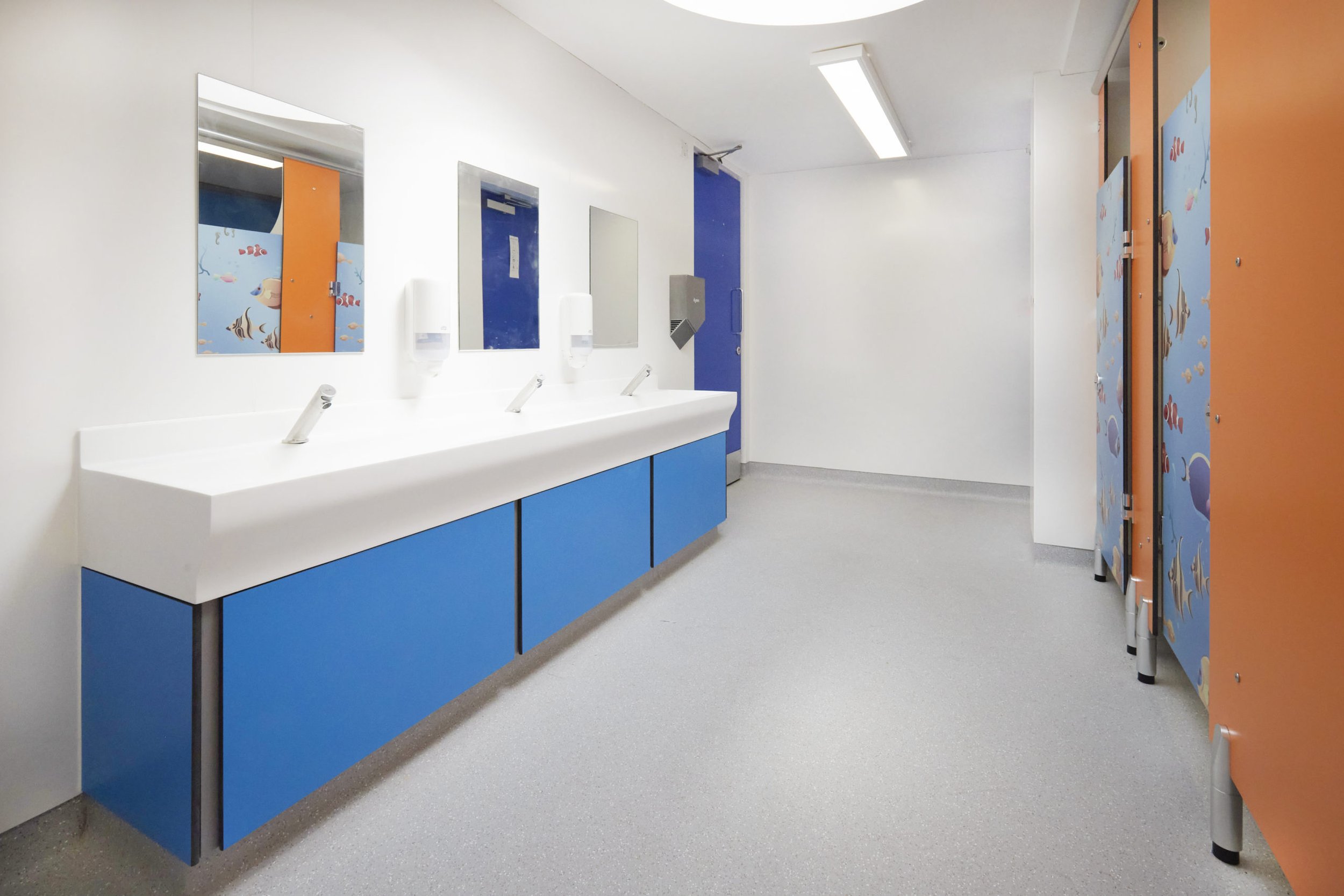 washroom with blue vanity unit and solid surface wash trough and mirrors above at upland school.jpg