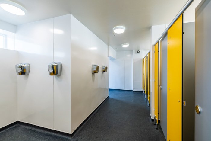 grey and yellow cubicles, white hygienic cladding and hand dryers at southwold toilets.jpg