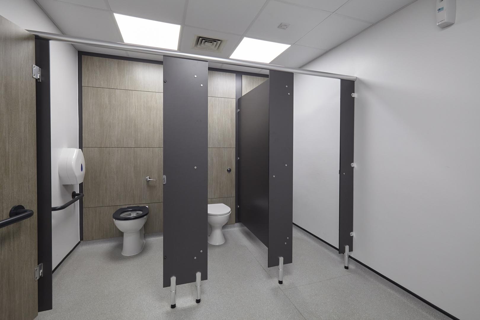 row of cubicles with one ambulent cubicle, full height duct panels in a woodgrain and grey colour scheme at leicester college.jpg