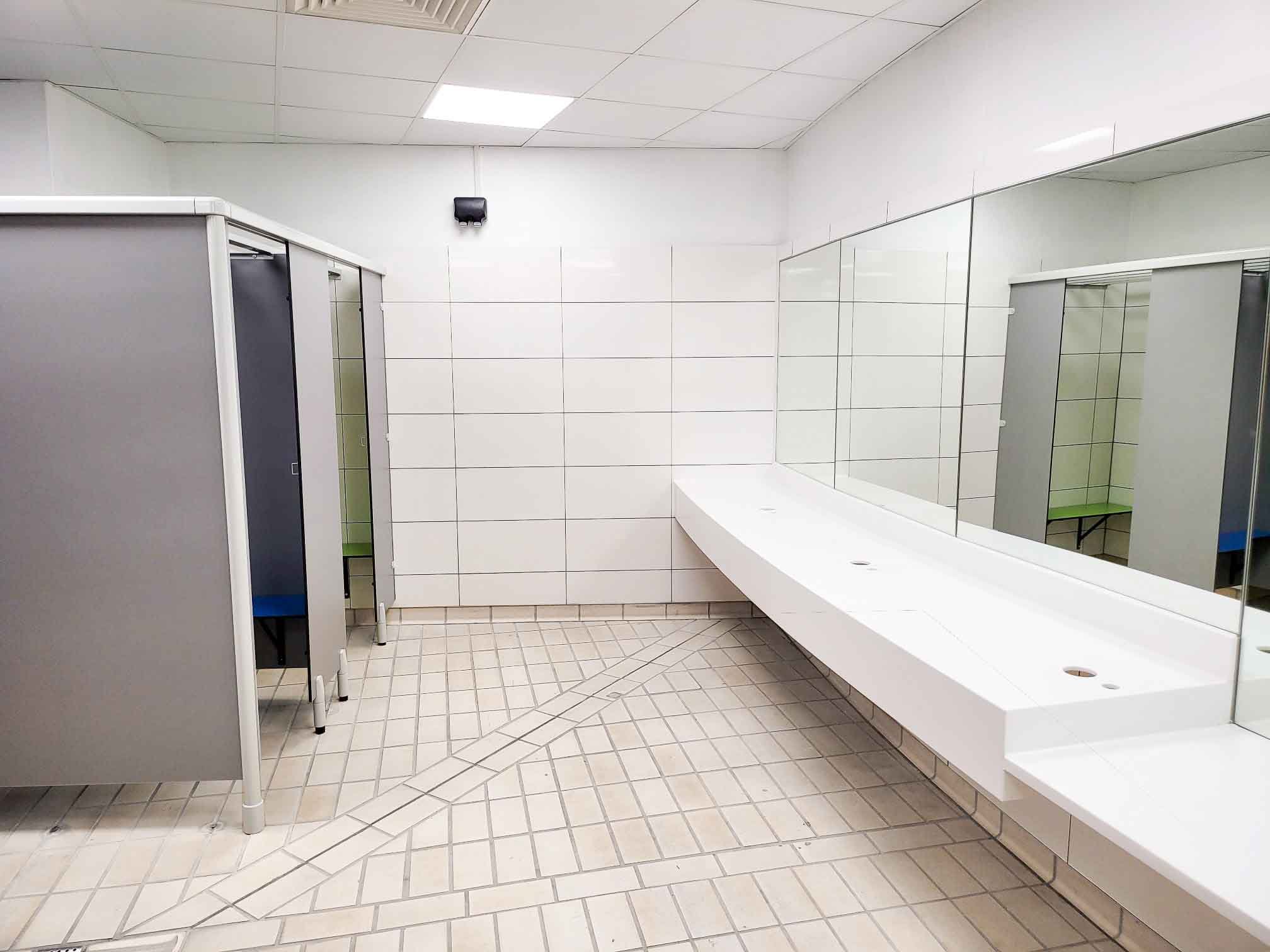 changing room at herons leisure centre with changing cubicles and a curved corian vanity area with mirrors.jpg
