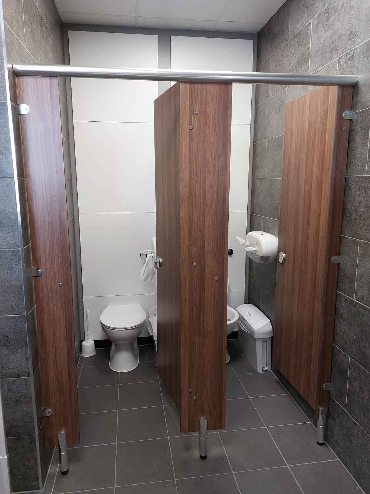 toilet cubicles with dark brown woodgrain cubicles, white full heigh duct panels and grey concrete tiling at kia oval.jpg