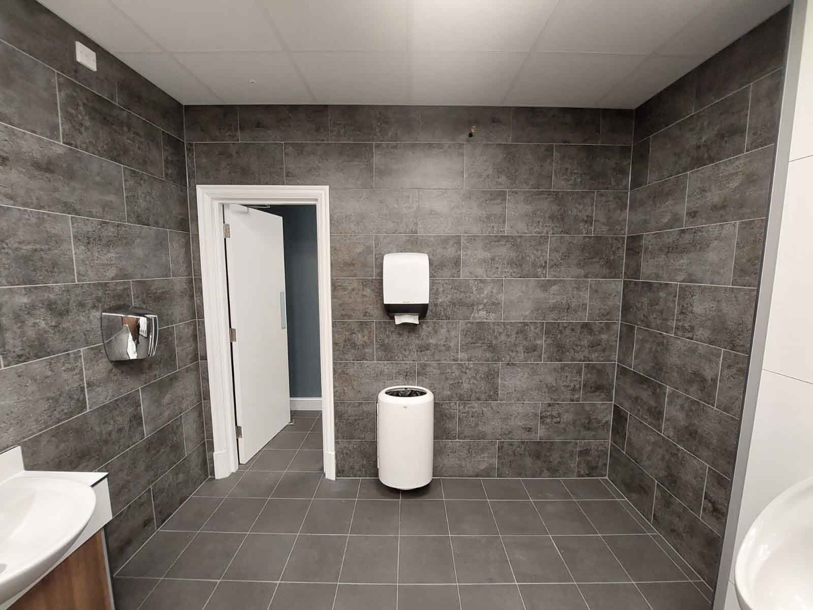 washroom entrance area with grey concrete tiles, a hand dryer, dispenser and bin at kia oval.jpg