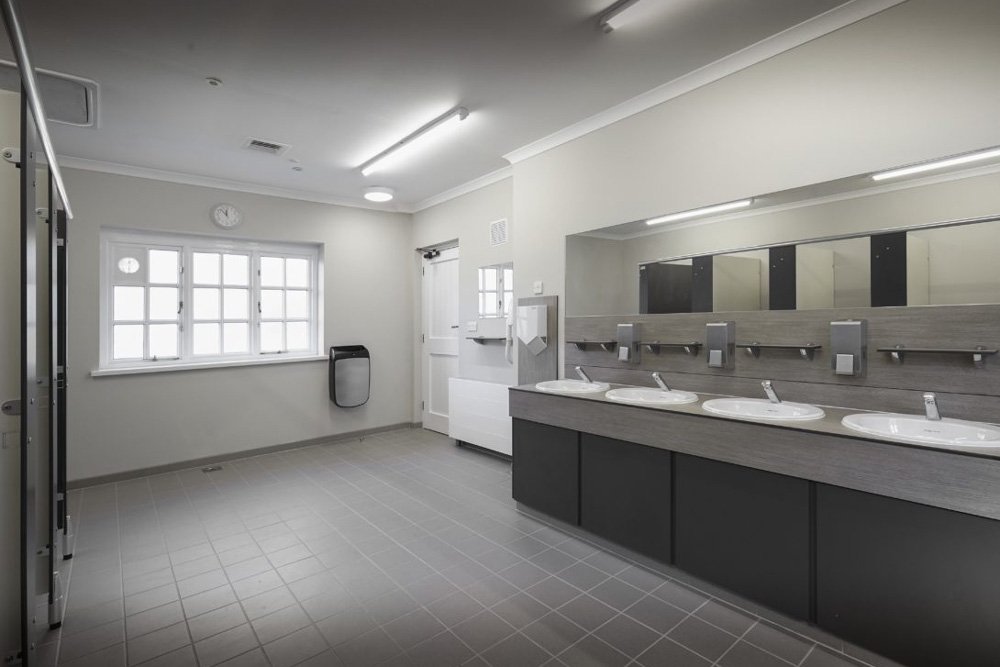 a washroom with handwash vanity unit area with a recessed sinks in a vanity top and a mirror and a splashback with shelves and dispensers at waterclose meadows campsite.jpg
