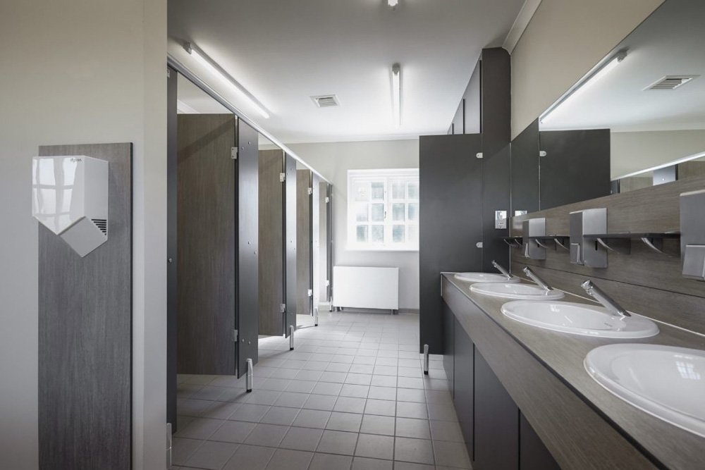 a washroom with cubicles, urinals and a vanity hand wash area in grey colour scheme with splashback and a hand dryer at waterclose meadows campsite.jpg
