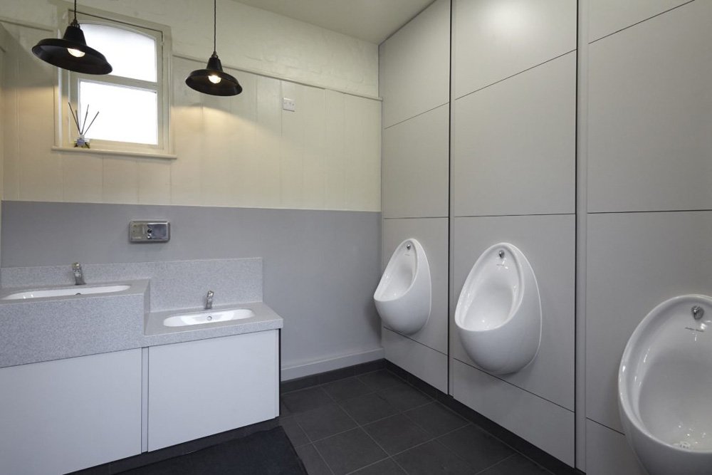 vanity unit with corian tops,  a lower height station and industrial lights above, duct panelling with urinals at hughenden manor.jpg